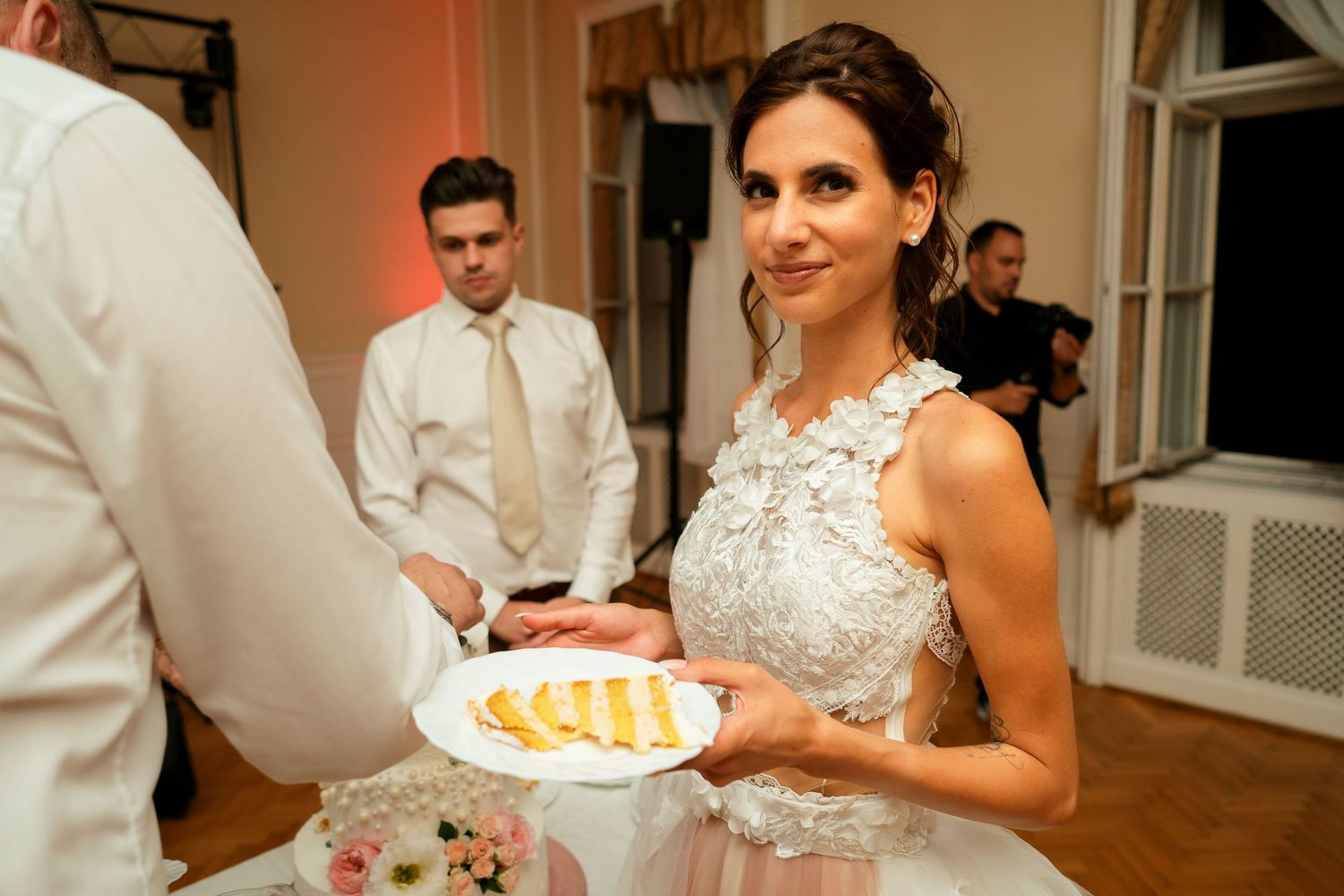 Wedding reception guest holding plate of food in elegantly decorated venue.