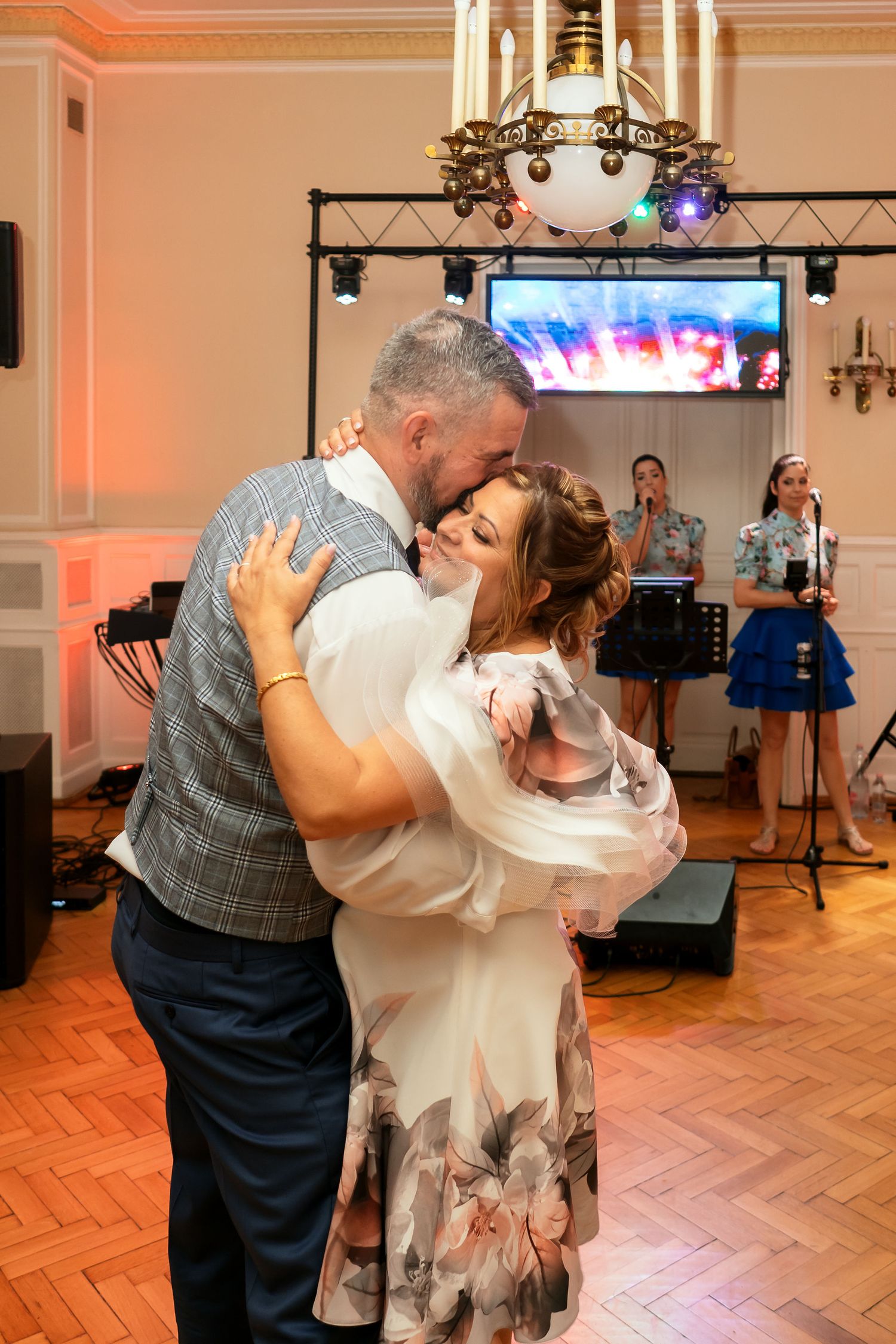 Couple sharing romantic dance moment under chandelier at wedding reception.