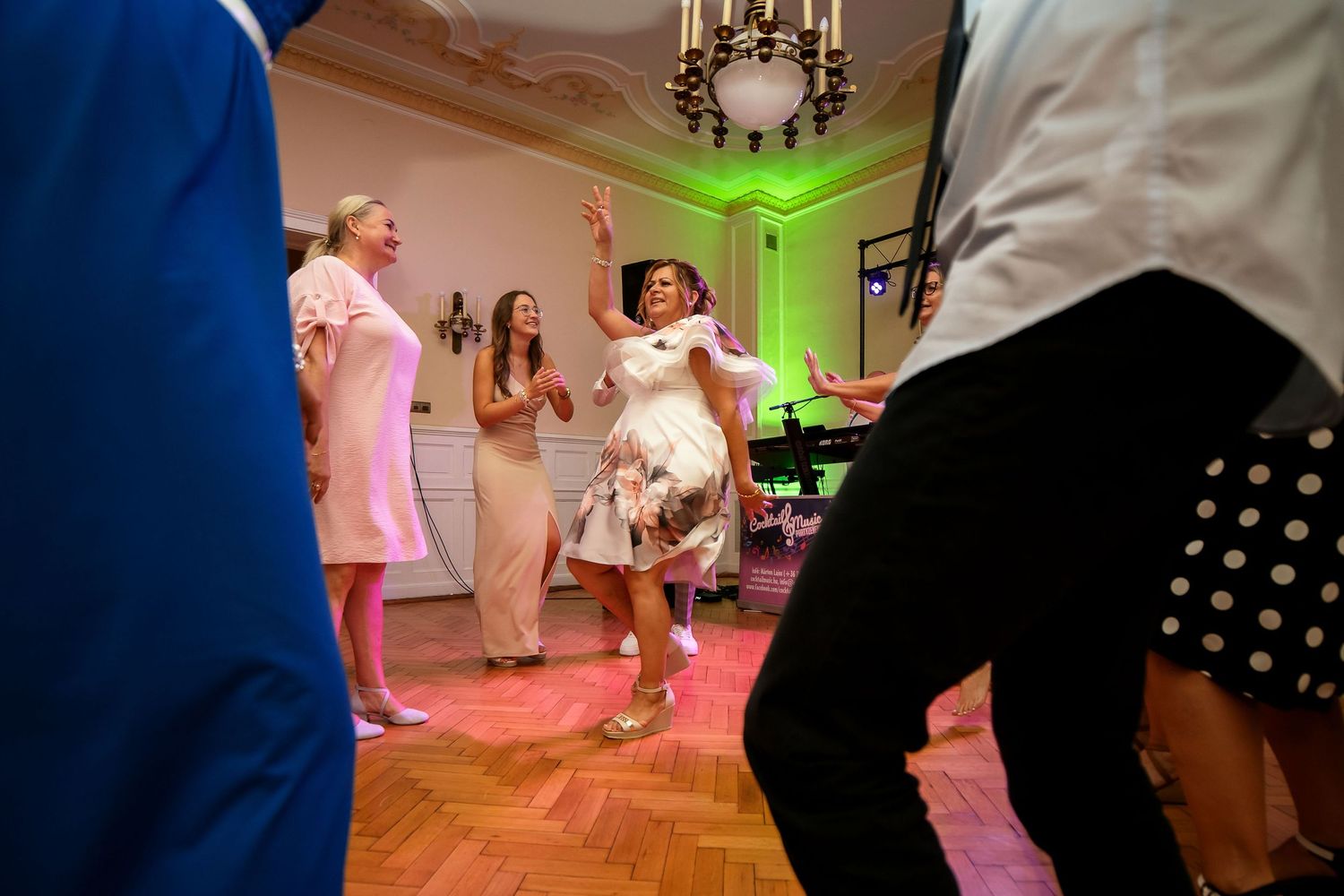 Wedding guests dancing and celebrating on illuminated dance floor.