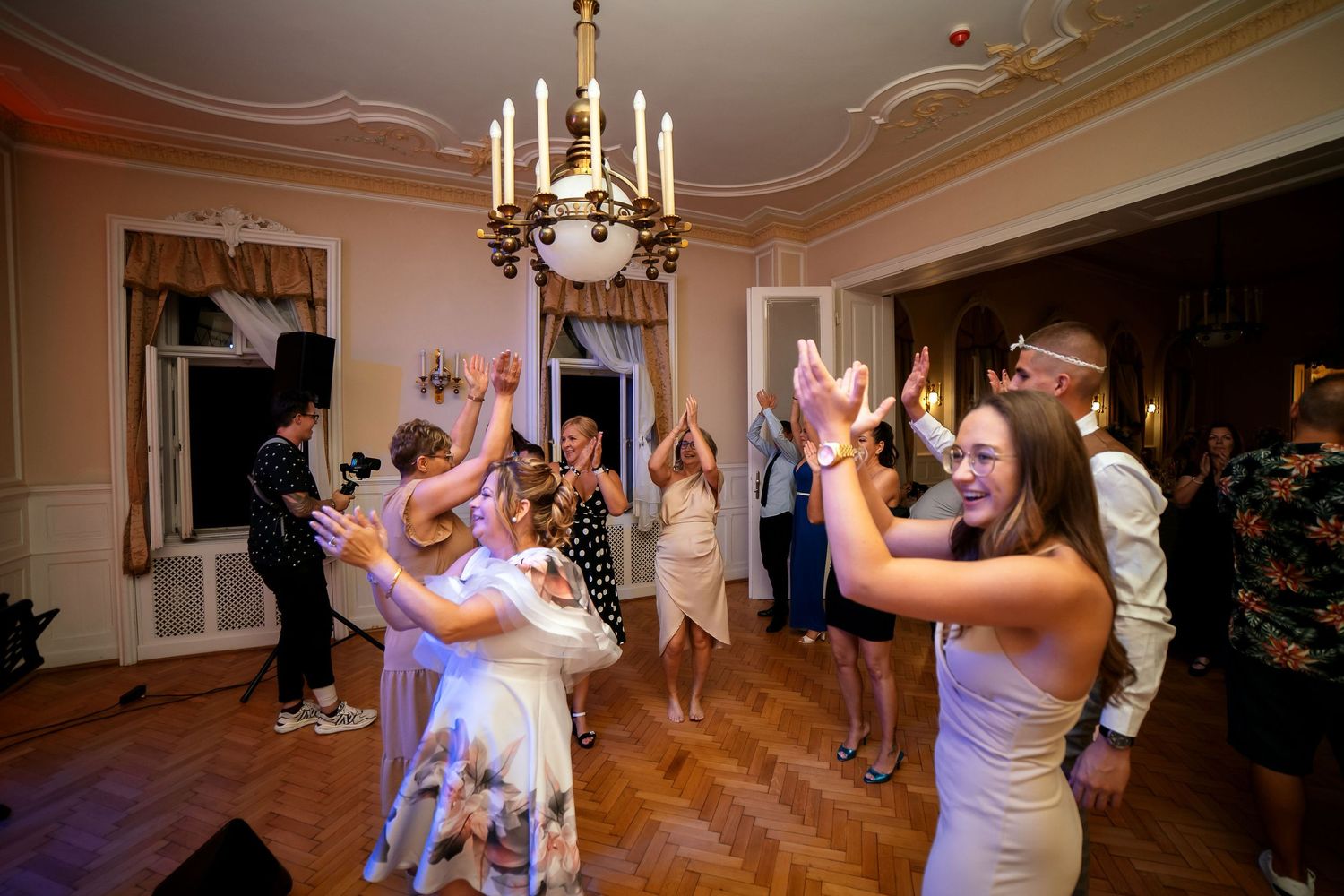 Enthusiastic dancers with hands in the air enjoying themselves at an indoor party venue.