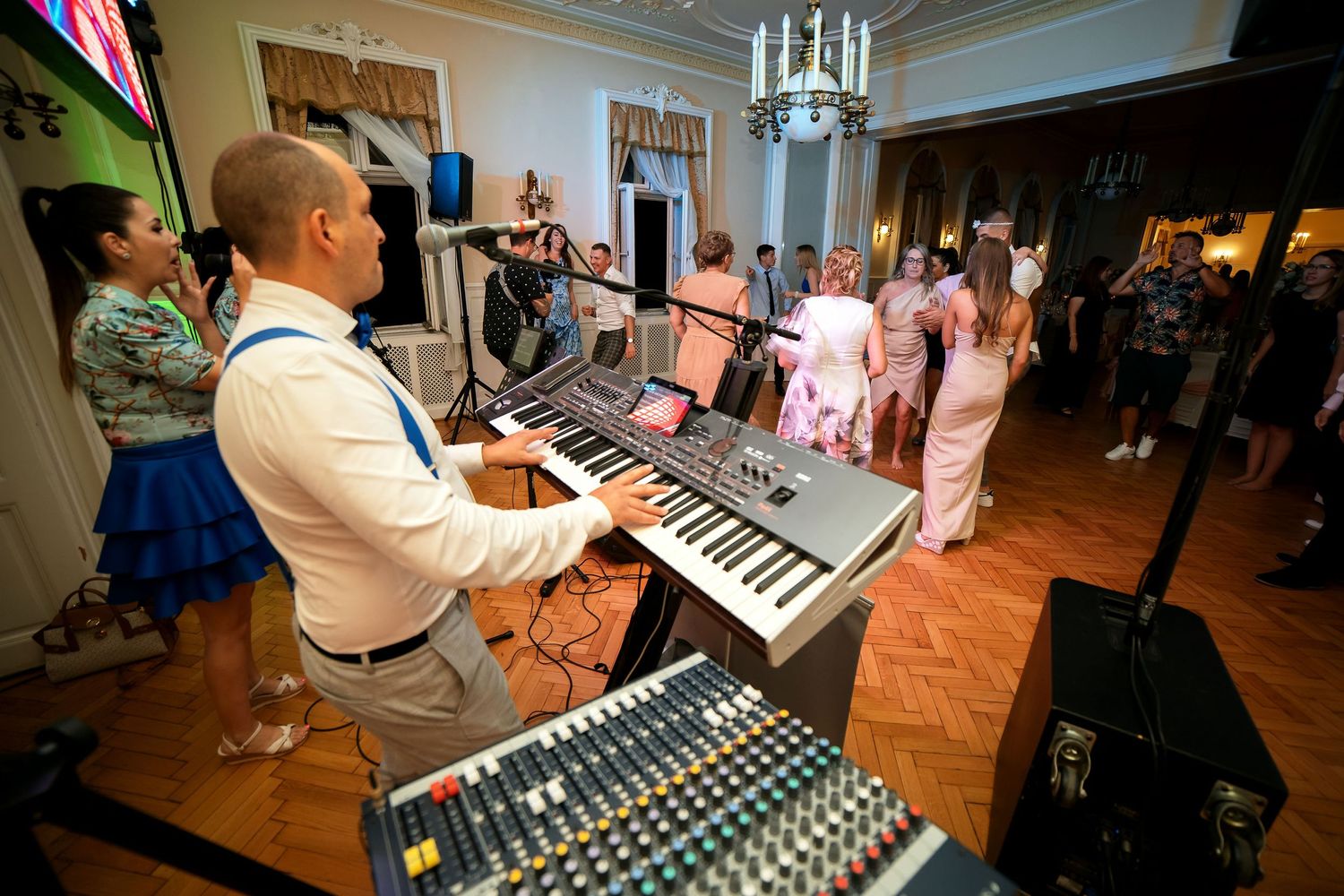 DJ operating keyboard and sound equipment at an elegant indoor party venue.