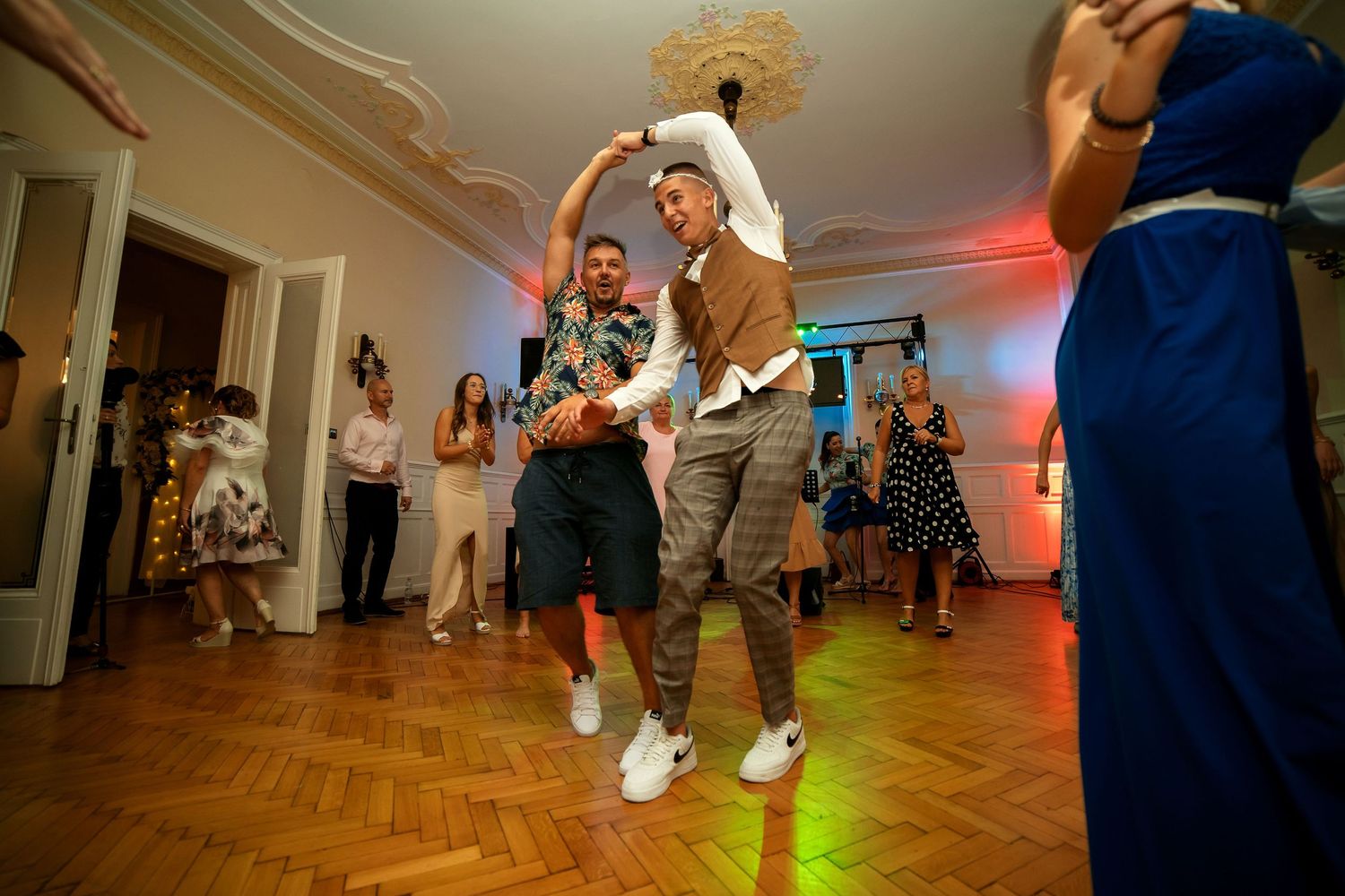 Energetic dancers moving to the music on a parquet dance floor under mood lighting.