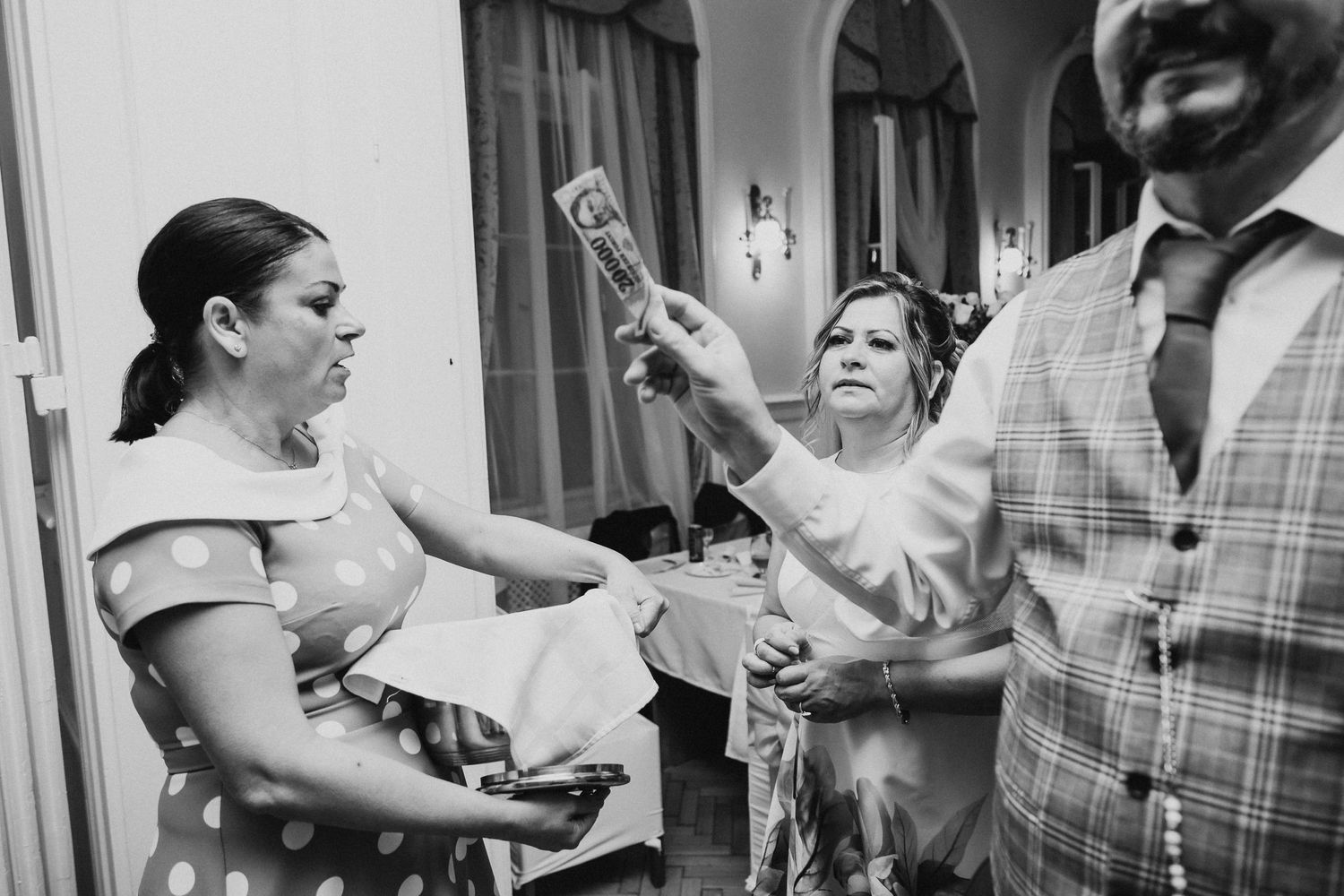 Black and white photo of party guests laughing and celebrating at an indoor event.
