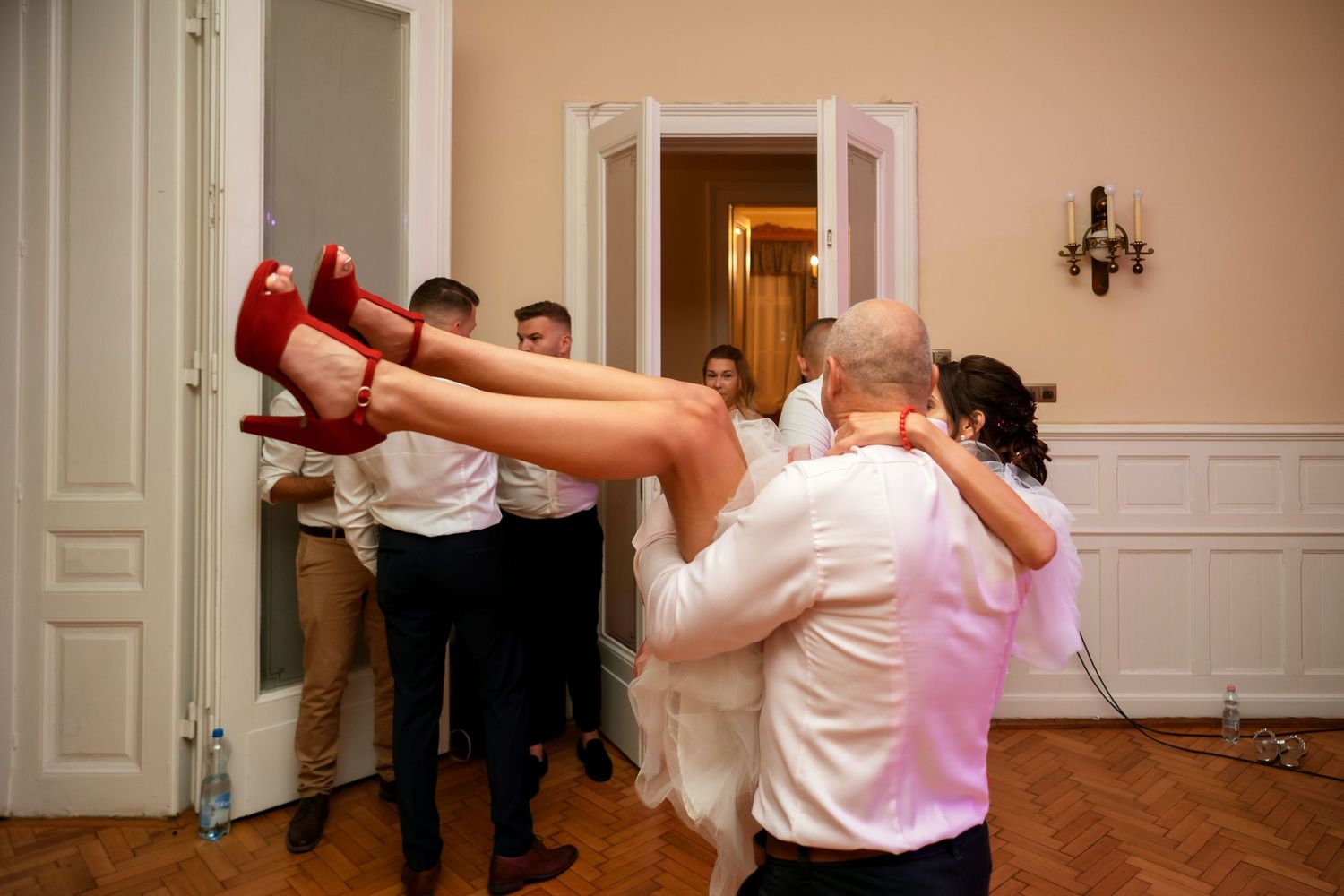 Dancing couple performs a dramatic dip move during a celebration on a parquet floor.