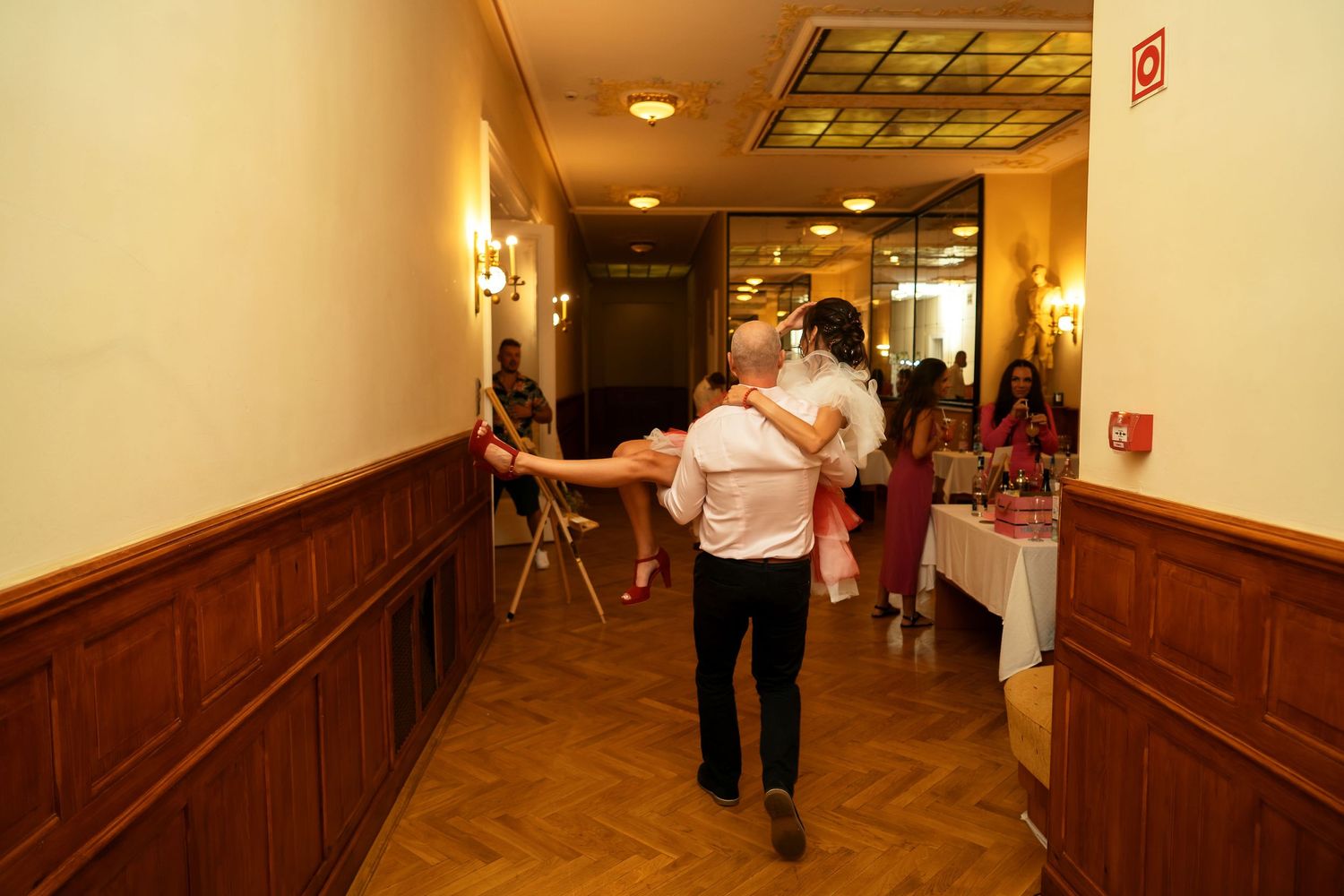 Group celebrating at a wedding reception in an elegantly decorated hallway with wood paneling.