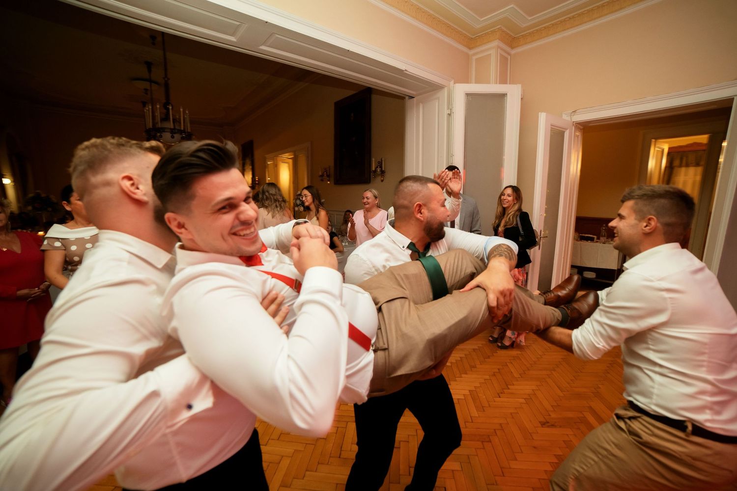 Lively dance moves being performed on a wooden parquet floor at a celebration.