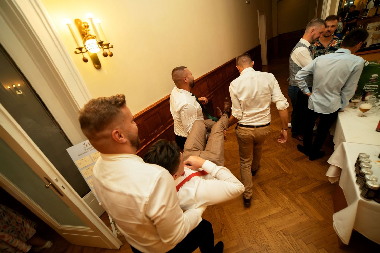Guests mingling in a hallway with wood paneling and wall sconces during an event.