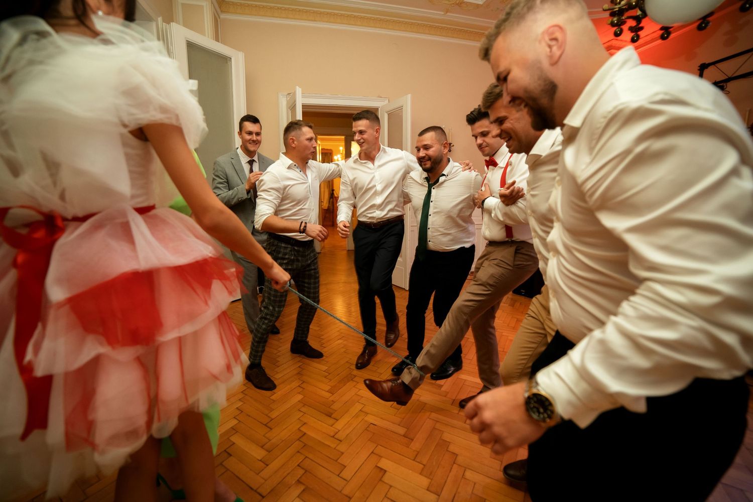 Dancers in white shirts surround someone in a red and white dress during an energetic dance party.