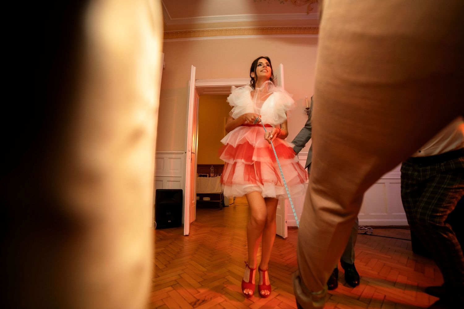 Person in a red and white tulle dress and red heels dances on a wooden floor.