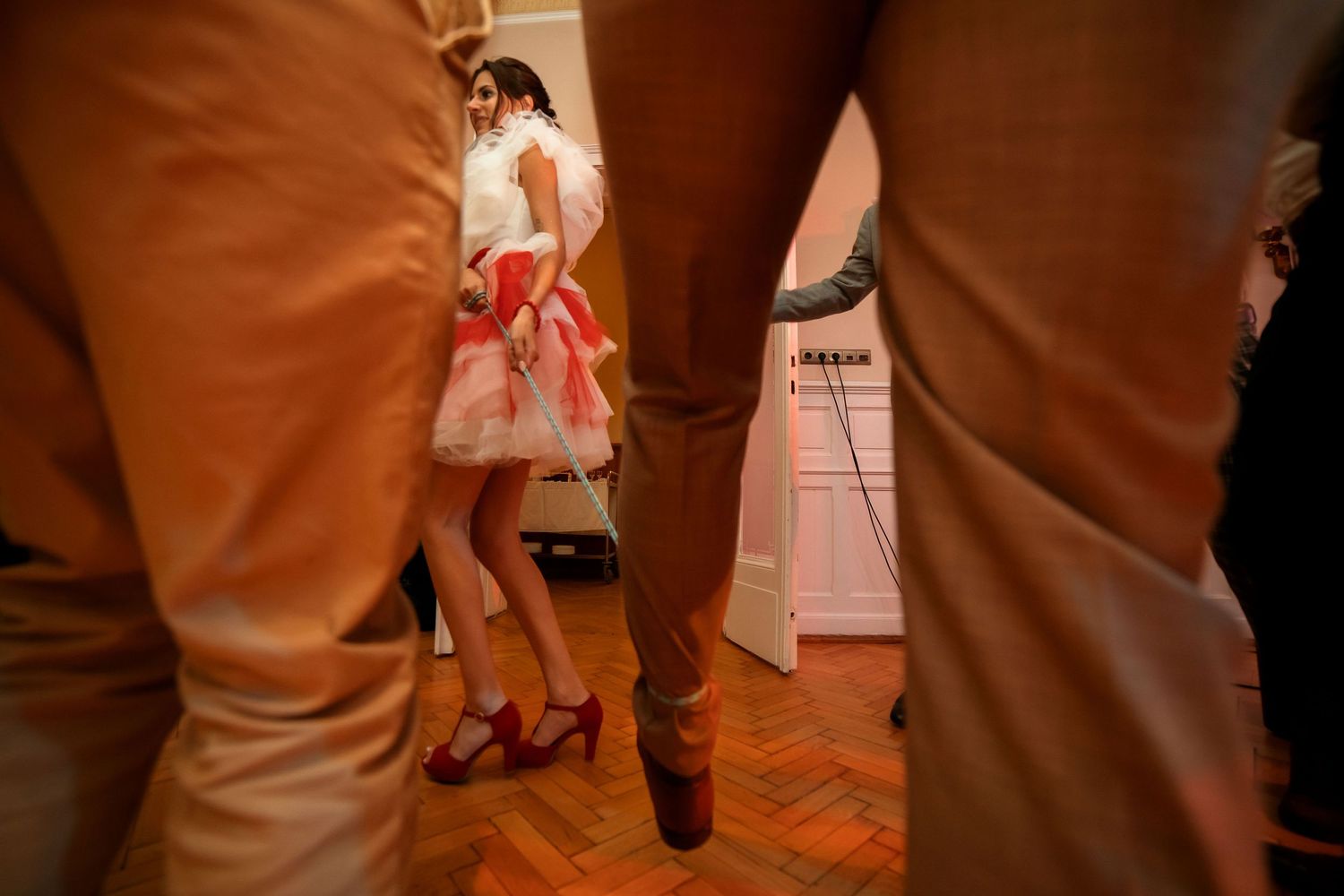 Red and white dress swirls on parquet flooring during a lively dance.