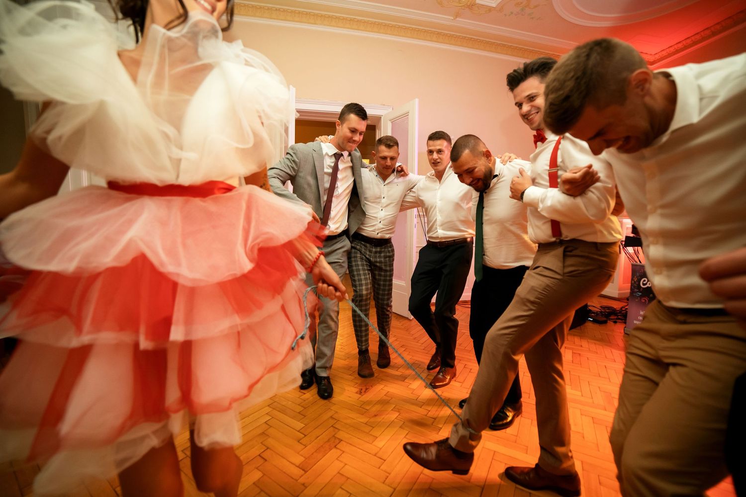Dancers gather in a circle during an energetic party on a wooden floor.