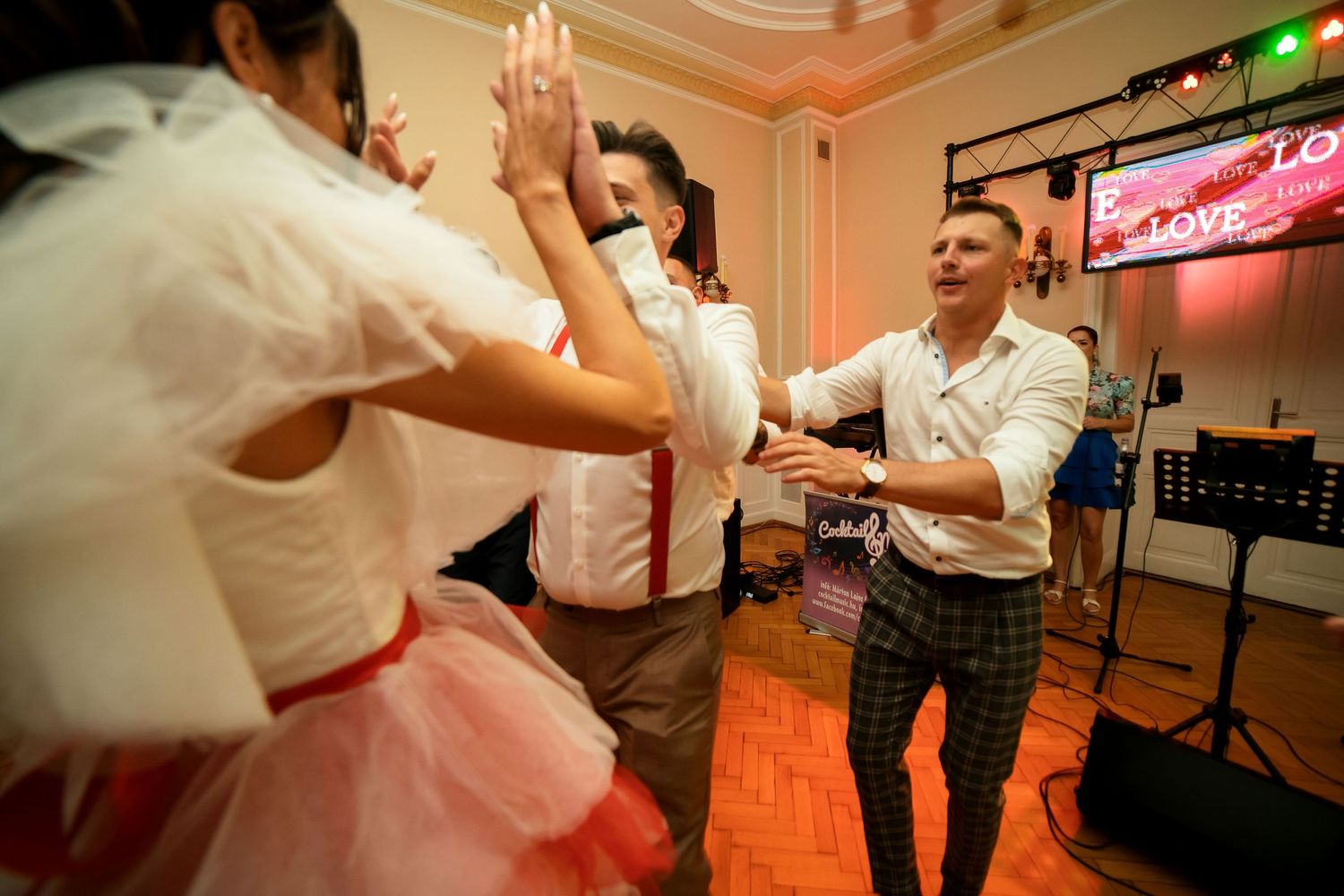 High-energy dancing with hands raised on a parquet dance floor.