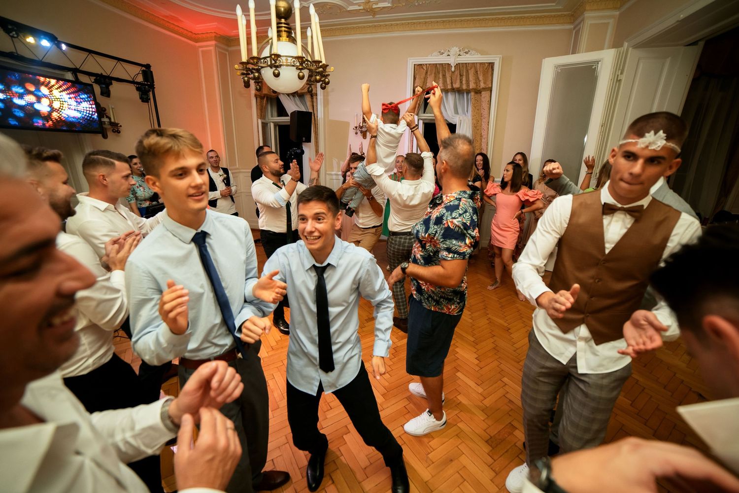 Celebratory dance moves at a wedding reception with colorful ambient lighting.