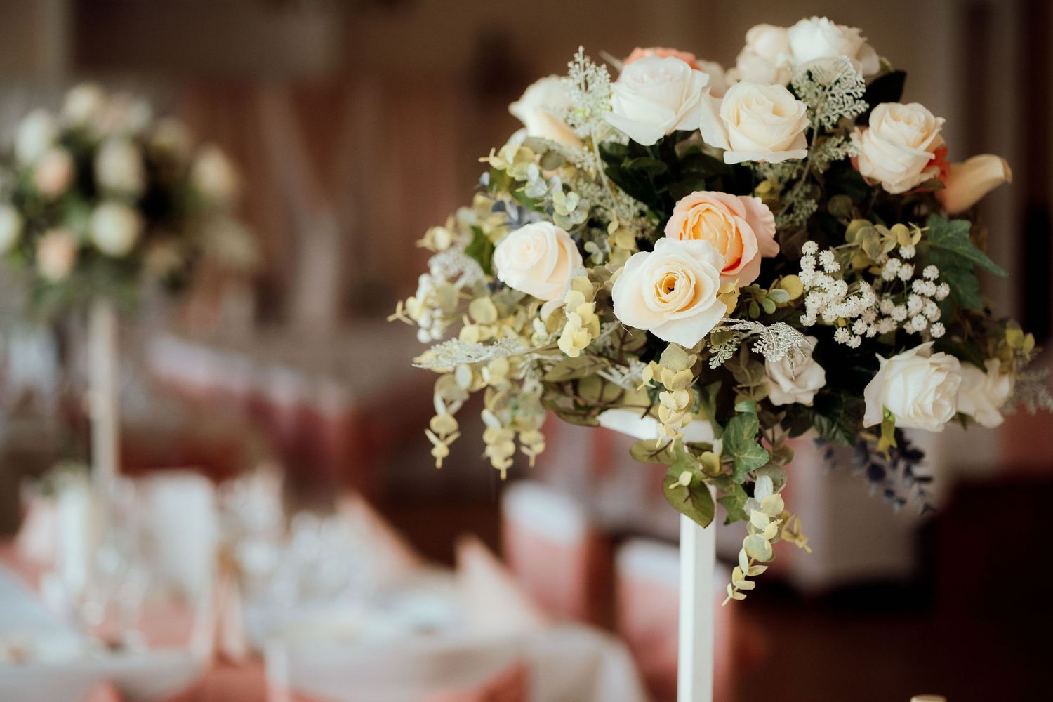 Elegant floral centerpiece featuring white and peach roses with delicate baby's breath.
