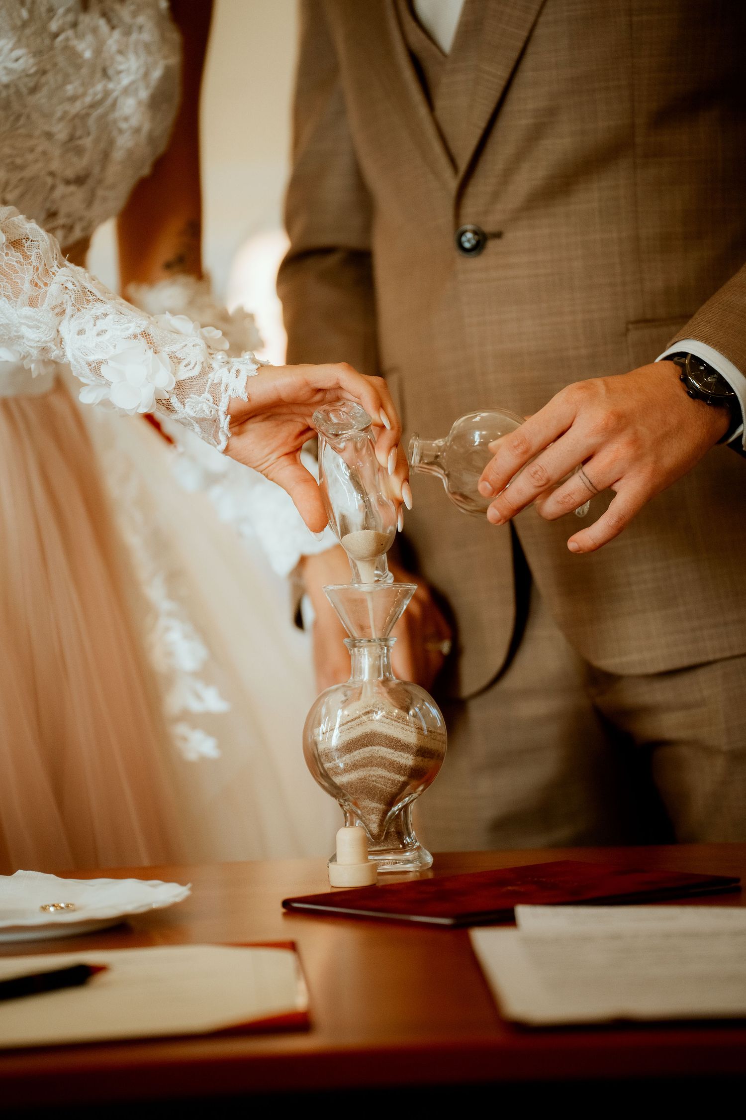 Close-up shot of hands pouring ceremonial sand during wedding ritual.