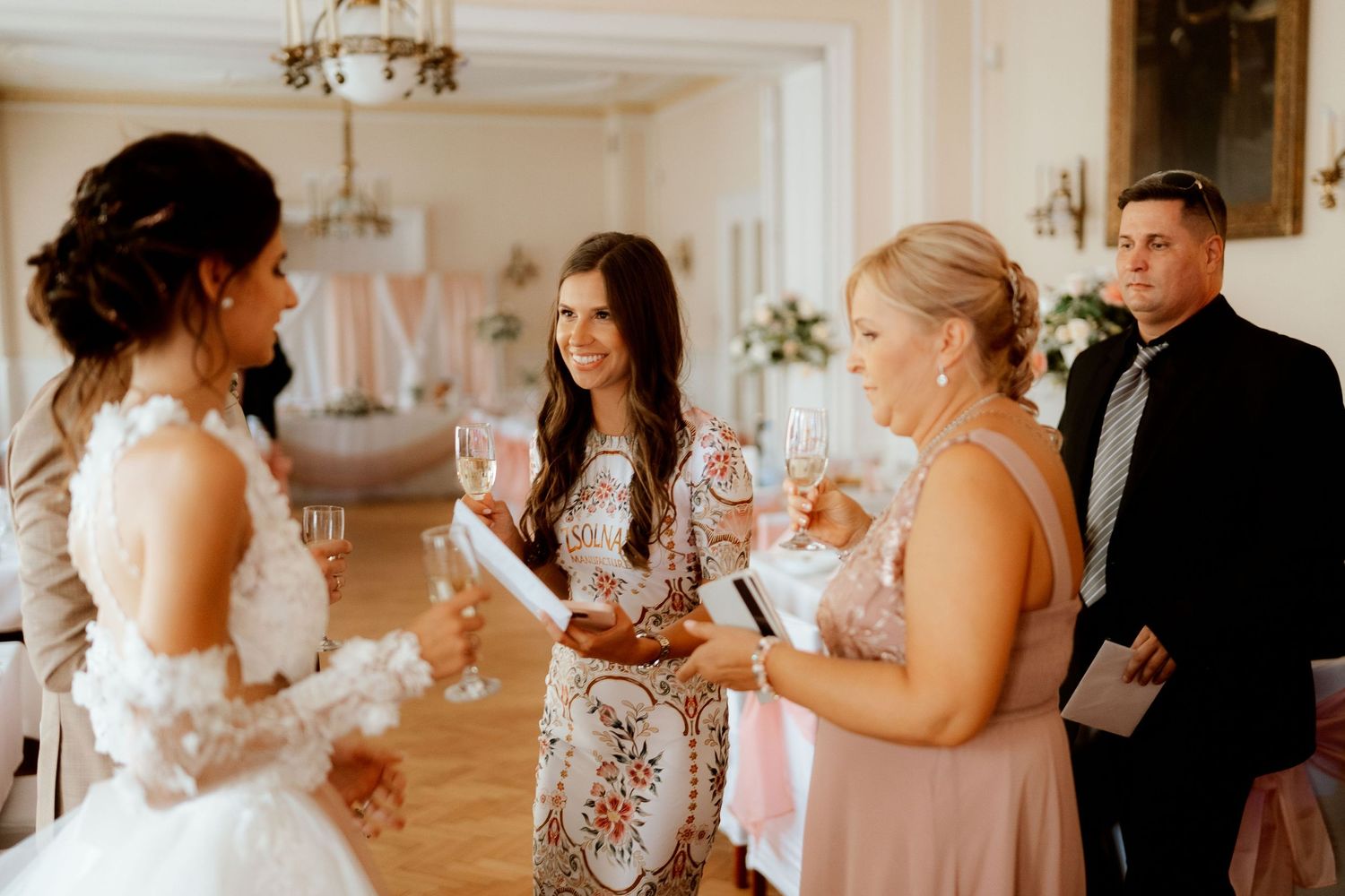 Wedding reception guests gather indoors for celebratory drinks and conversations.