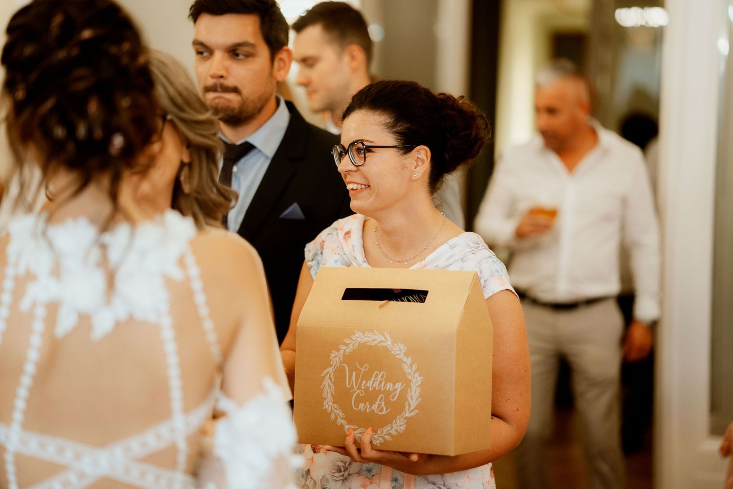 Wedding guests gathered in a hallway with someone holding a decorative paper bag.