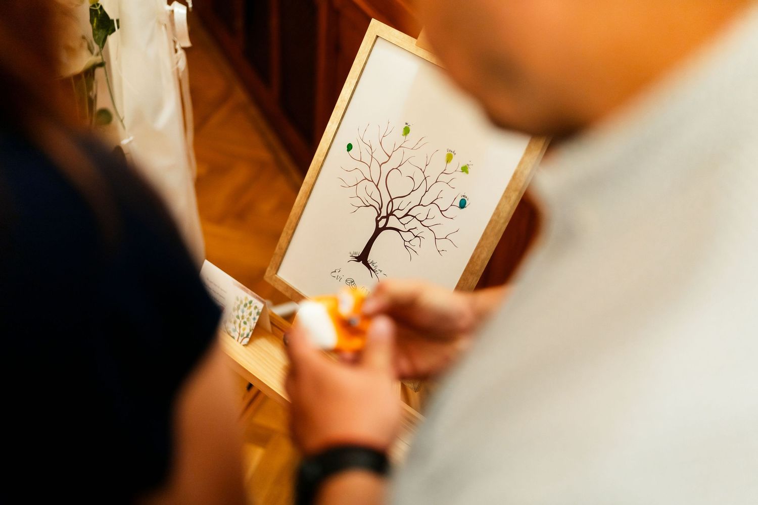 Close-up of hands holding a guestbook featuring a decorative tree illustration at a wedding.