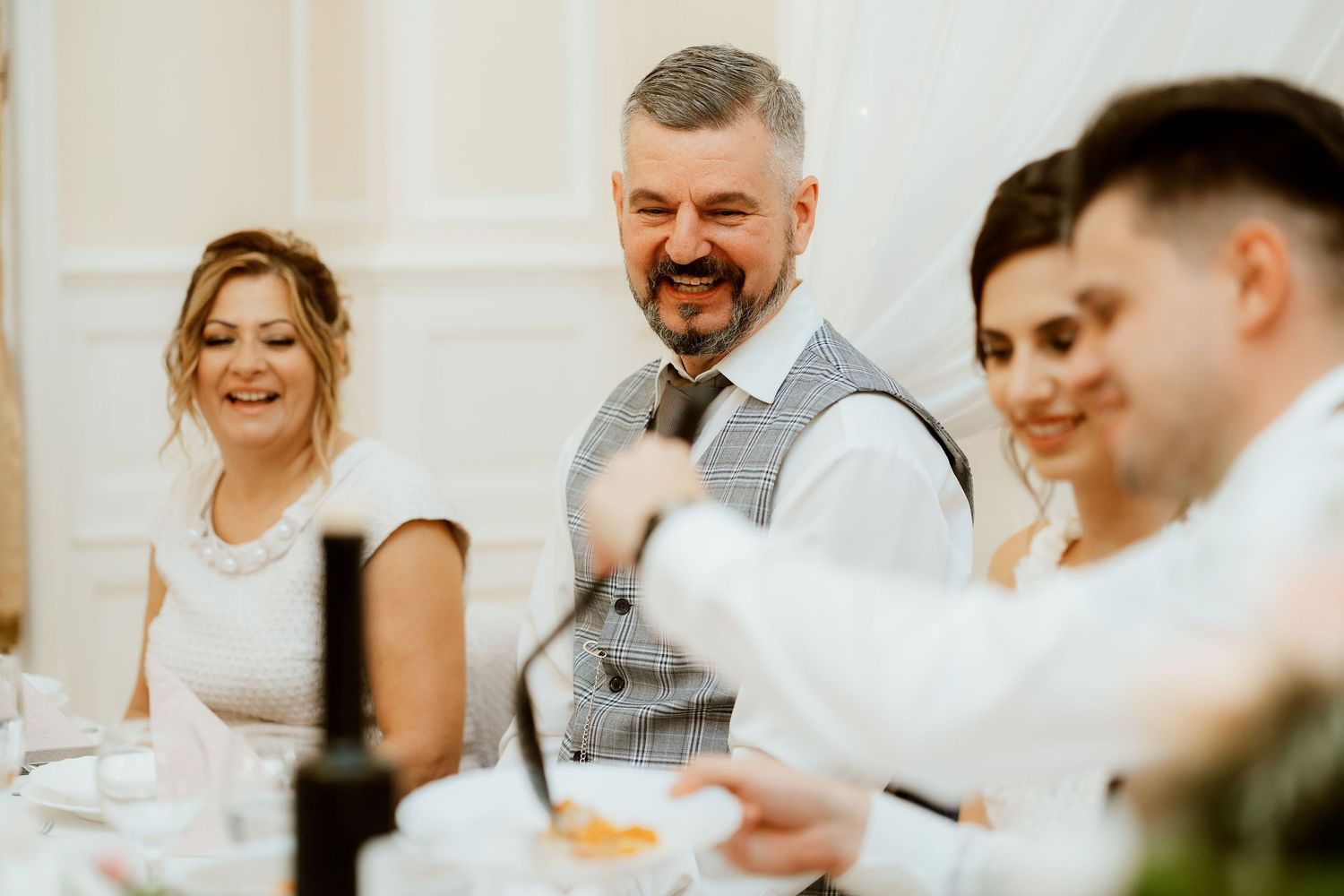 Wedding party members laughing during reception dinner festivities.