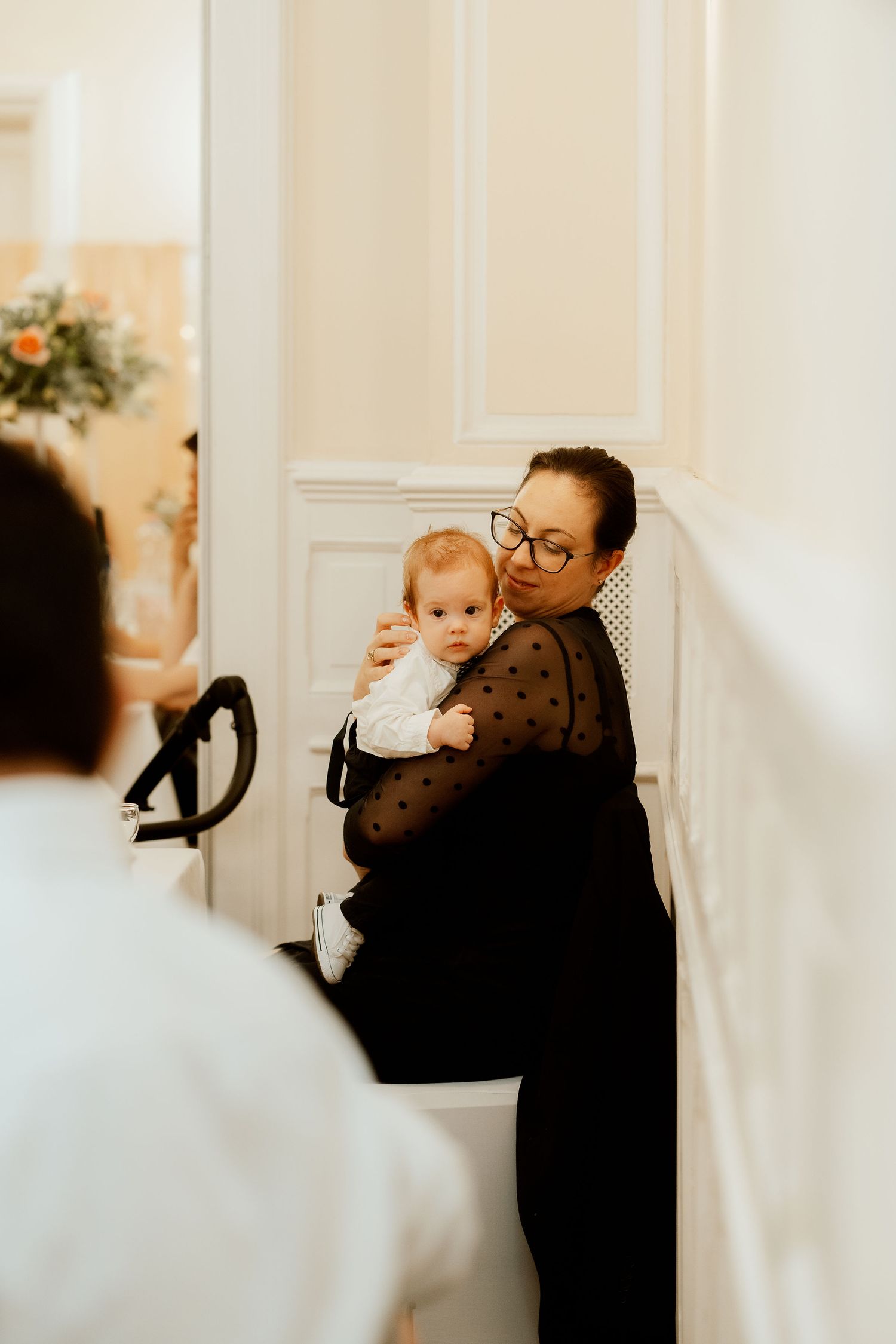 Tender moment captured at wedding reception with guest holding baby.