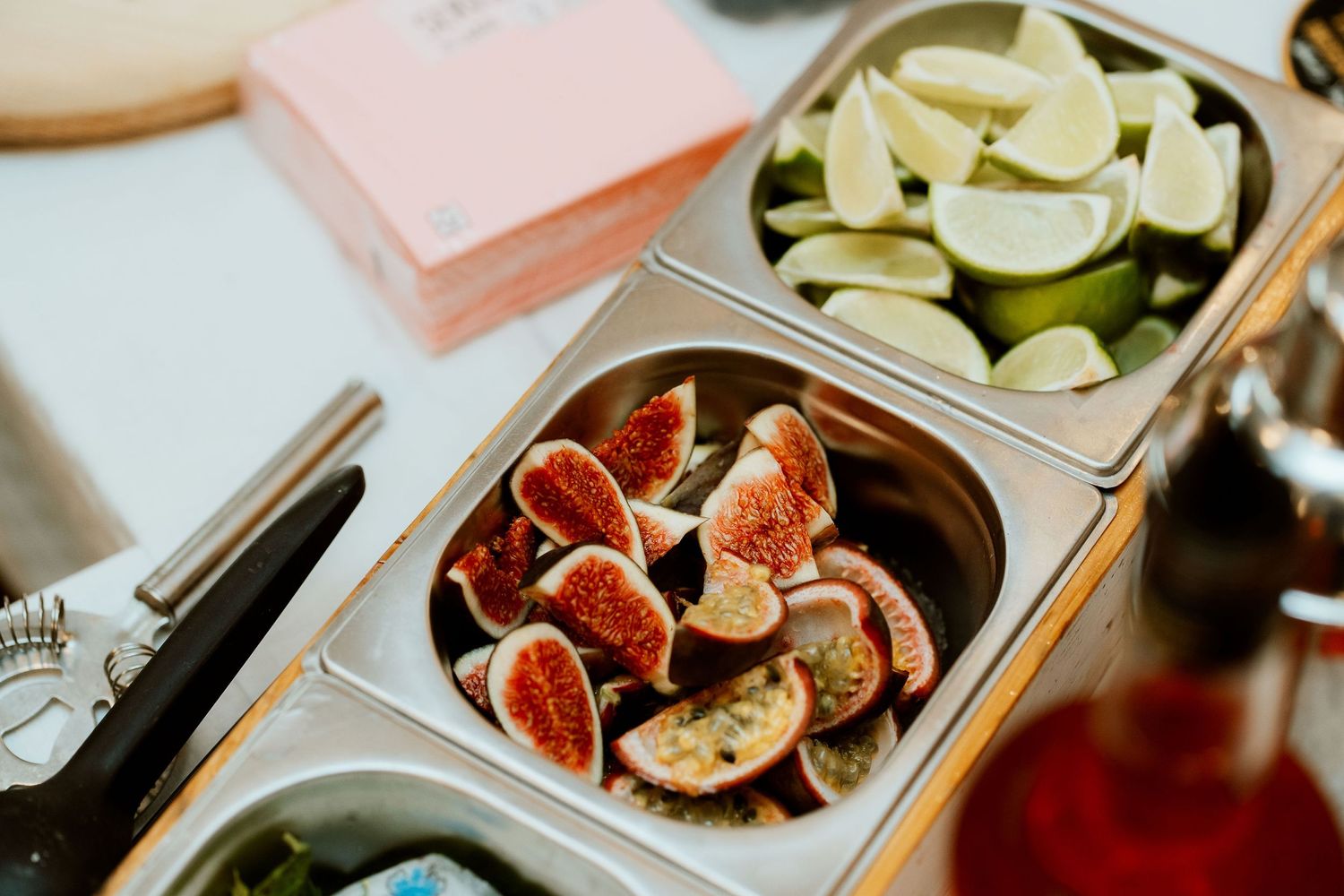 Fresh sliced figs and lime wedges displayed in metal serving trays at a catered event.