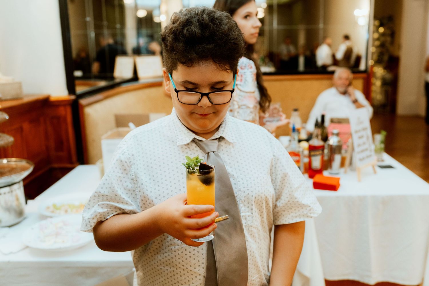 A young guest enjoying an orange beverage during the reception.