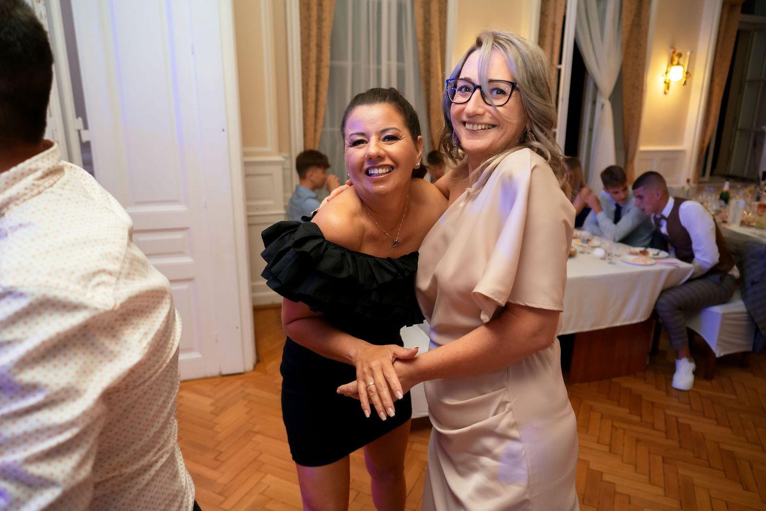 Two guests share a joyful moment on the dance floor at an elegant indoor reception.