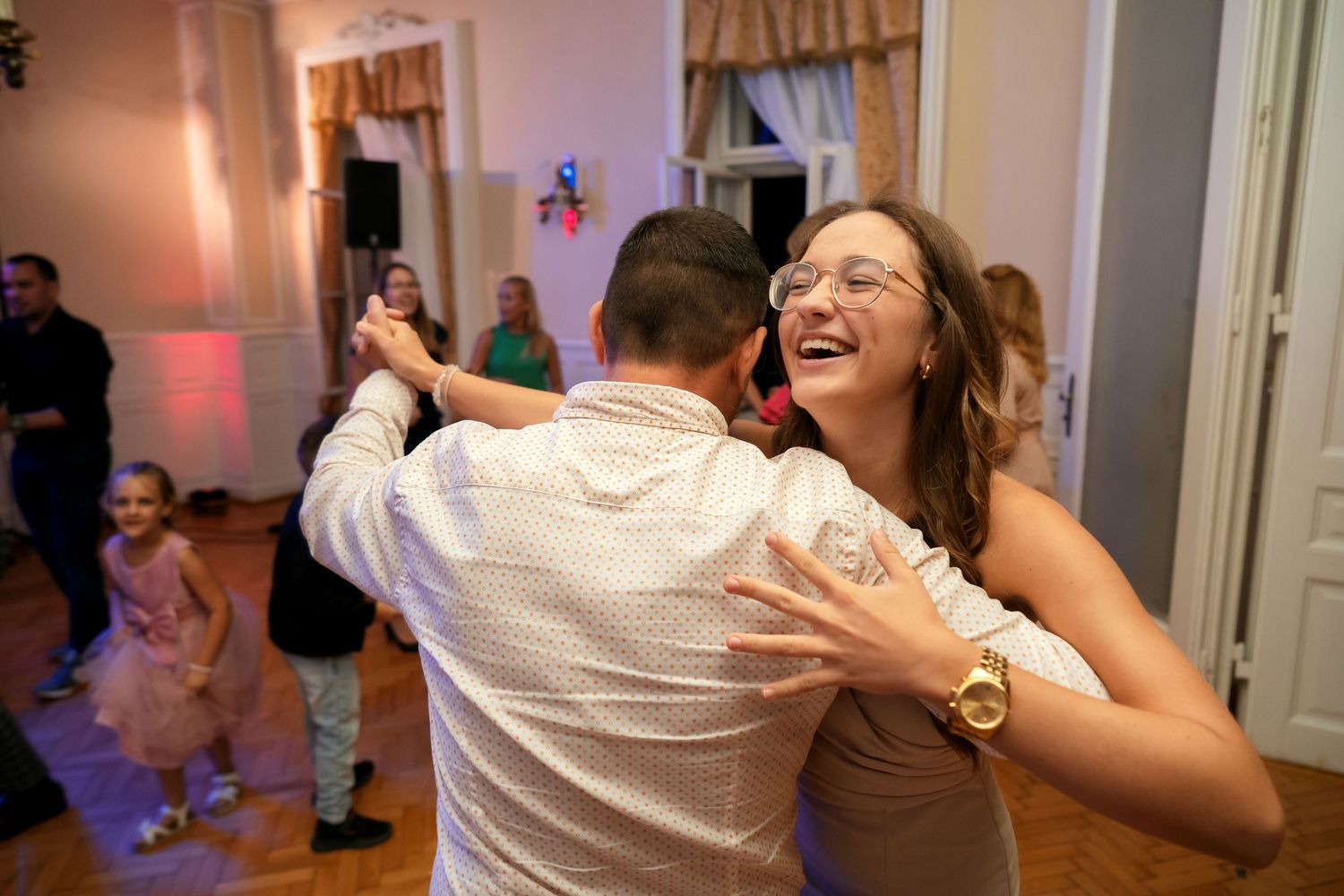 Guests dancing and laughing together at a lively indoor wedding reception.
