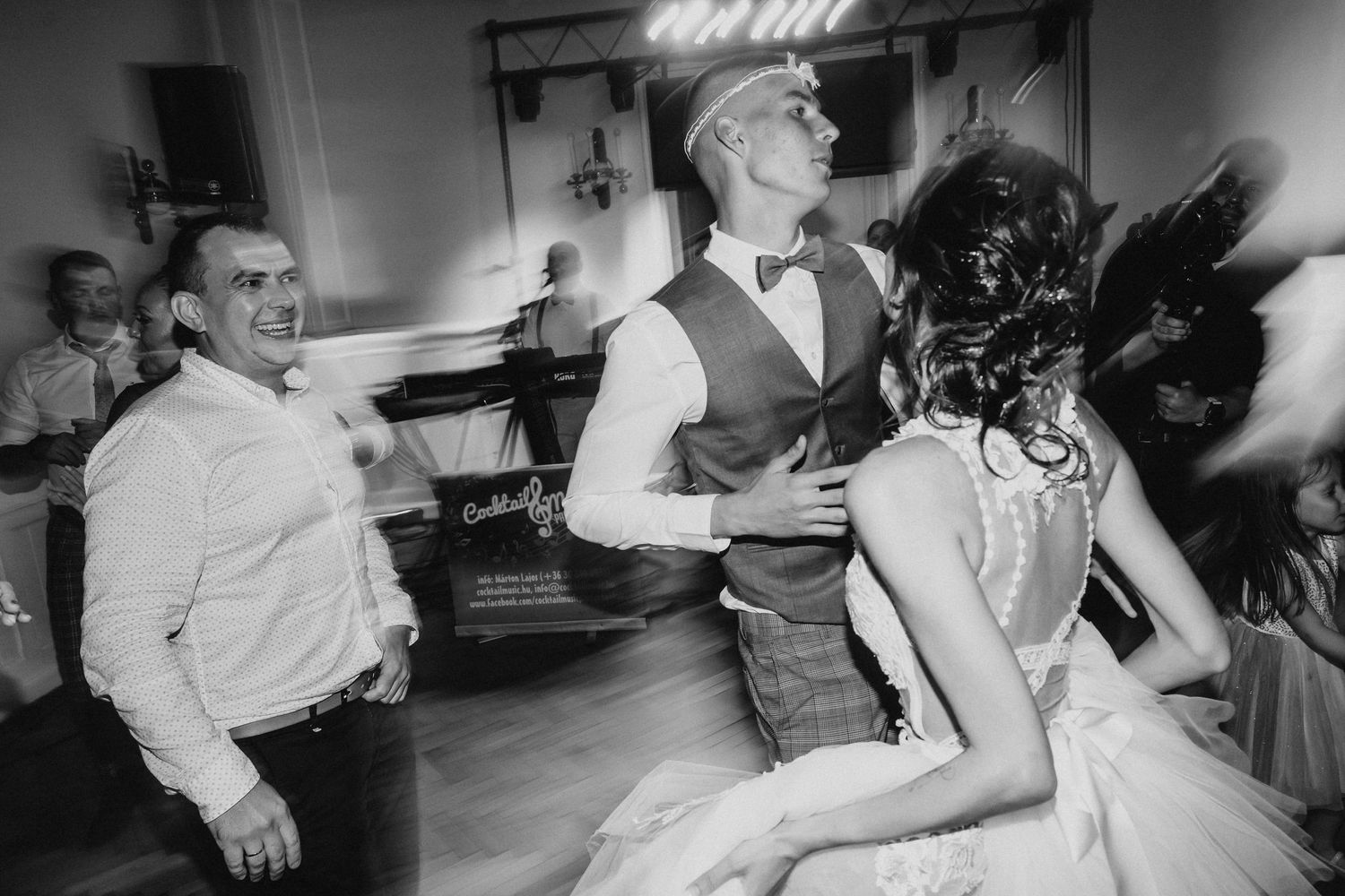 Black and white photo of guests dancing during a festive reception with band equipment visible.