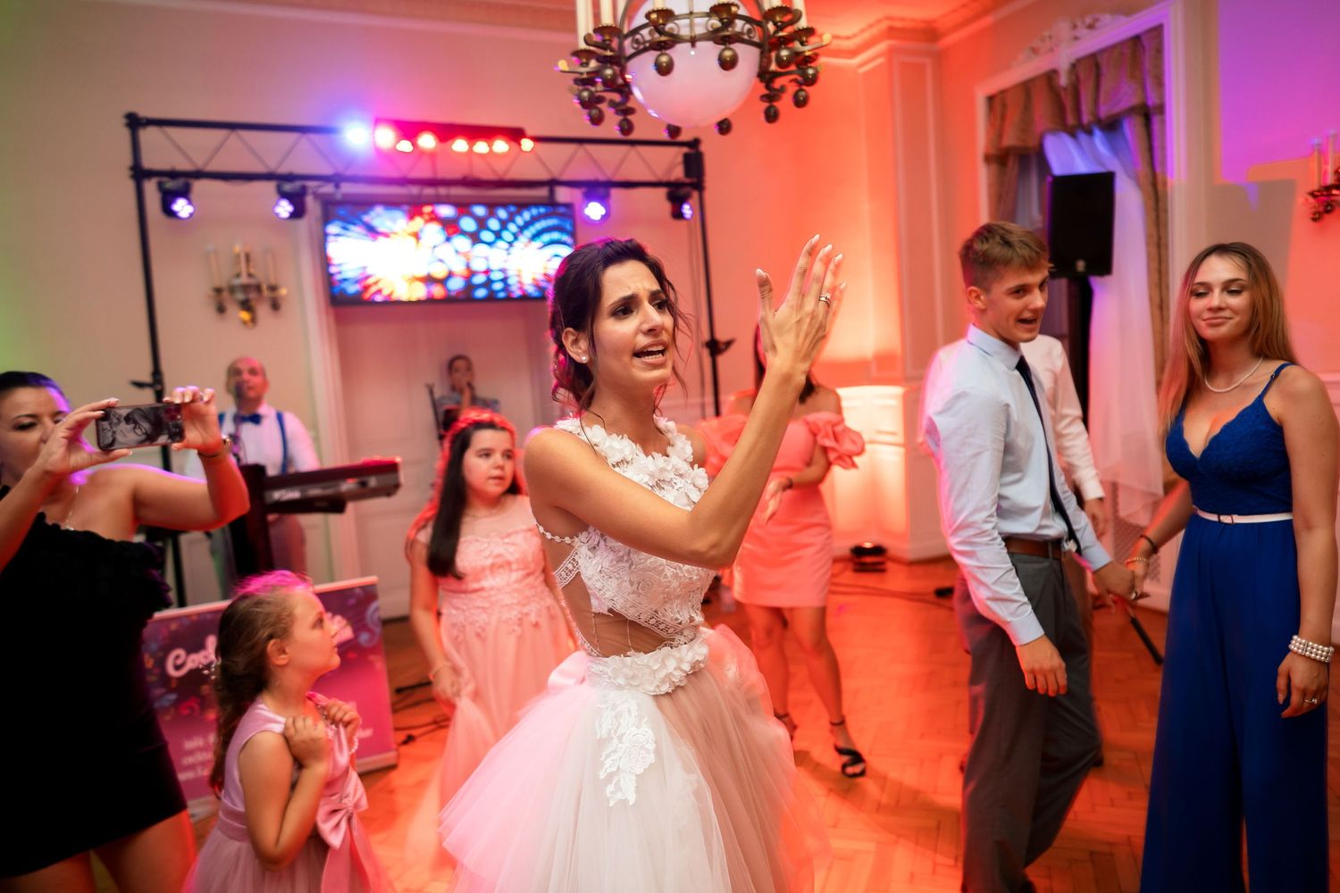 Wedding reception dance floor illuminated with pink and purple lighting during celebrations.