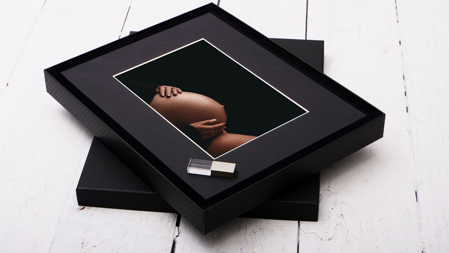 Professional matted black frame with photograph displayed on white wooden surface.