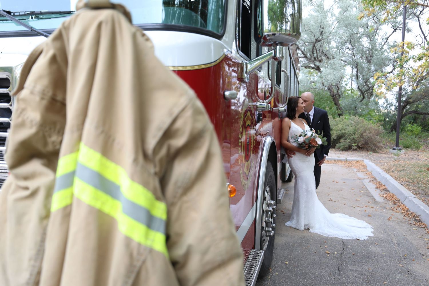Wedding photo featuring a fire truck with a firefighter in turnout gear.