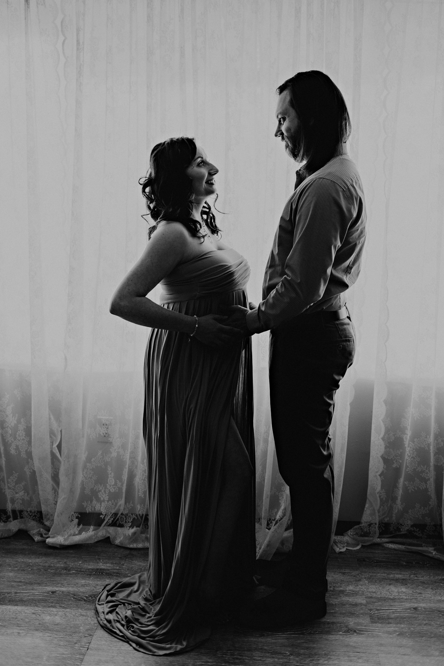 Black and white silhouette of a couple embracing, with the woman wearing a flowing maternity dress.