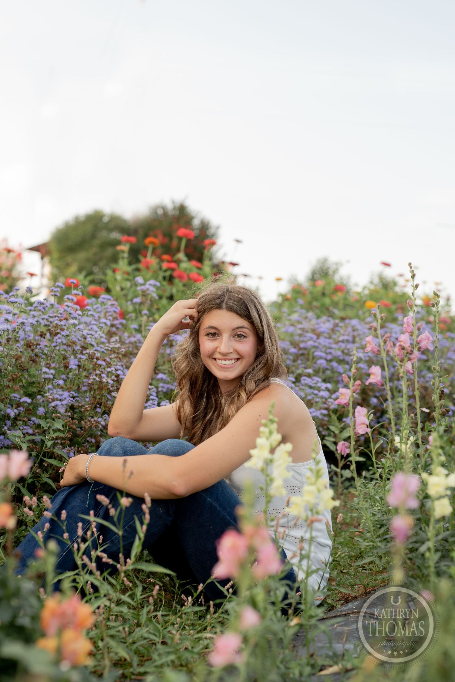 Person relaxing among colorful wildflowers and purple asters on sunny summer day.
