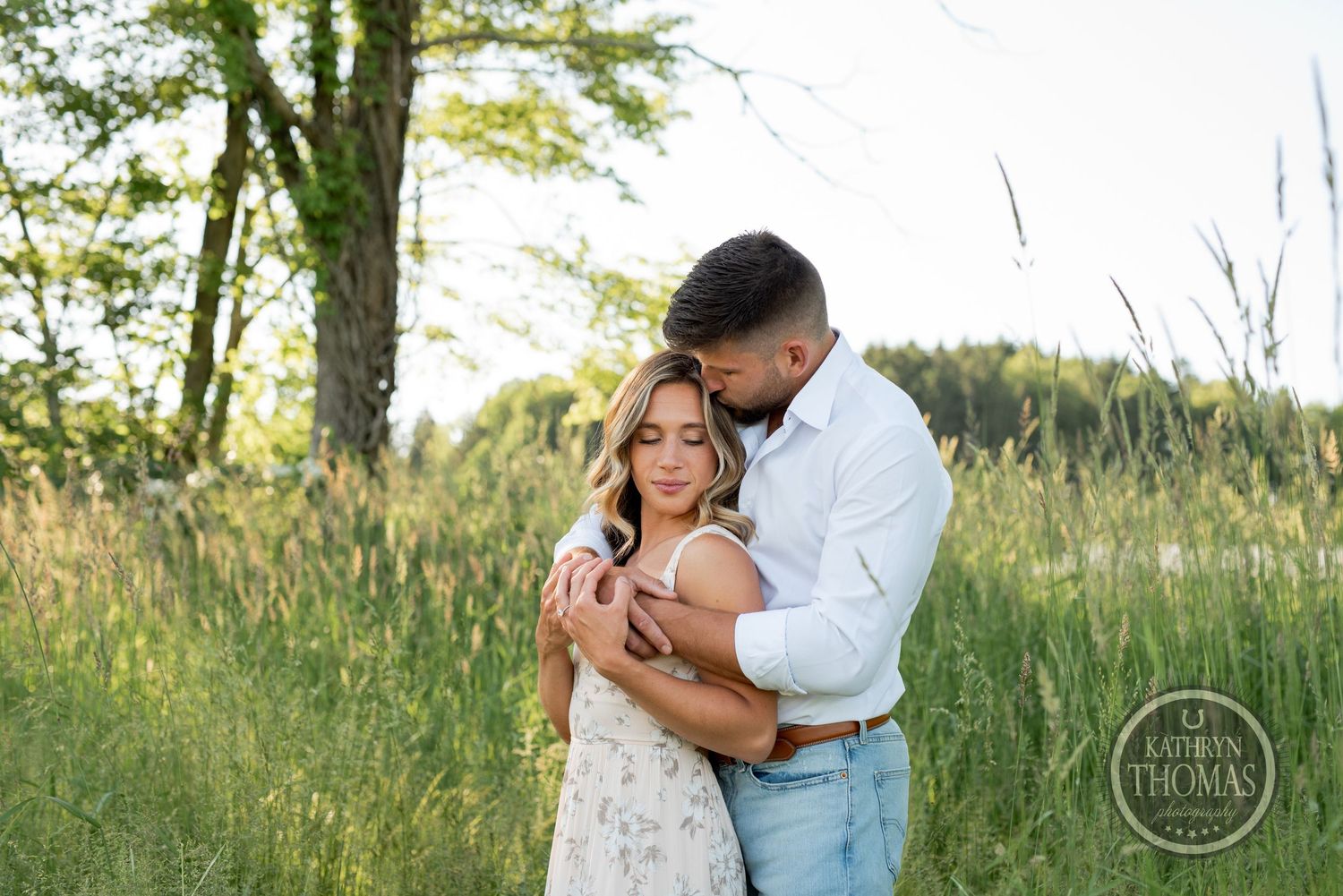 An intimate portrait of a couple embracing in a summer meadow with golden light.