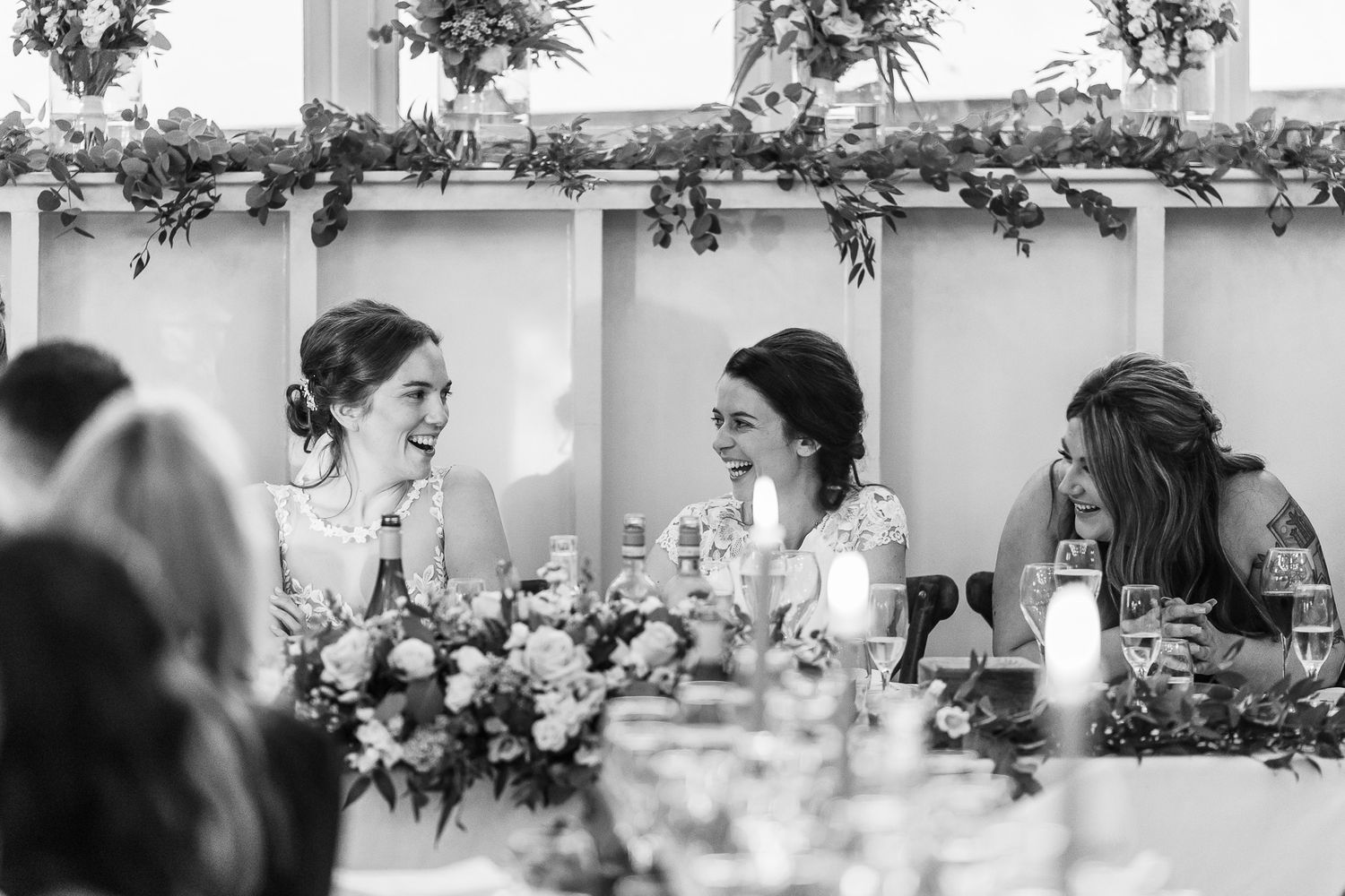 Candid black and white photo of guests enjoying conversation at an elegant wedding reception.