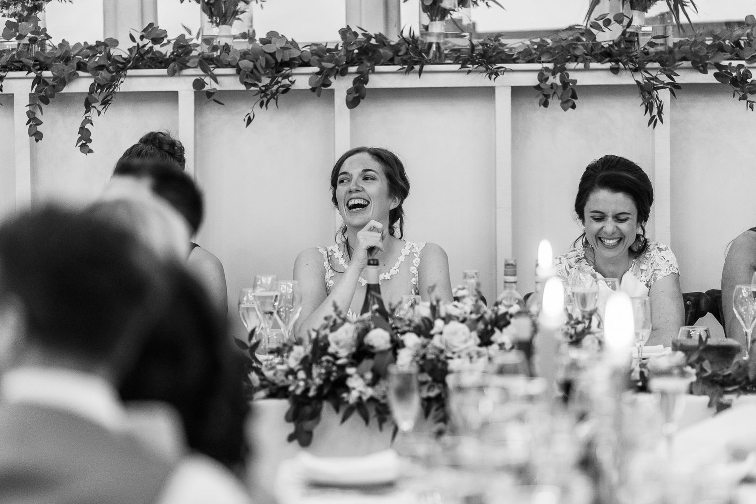 Emotional reactions capture genuine laughter and joy during wedding reception speeches.