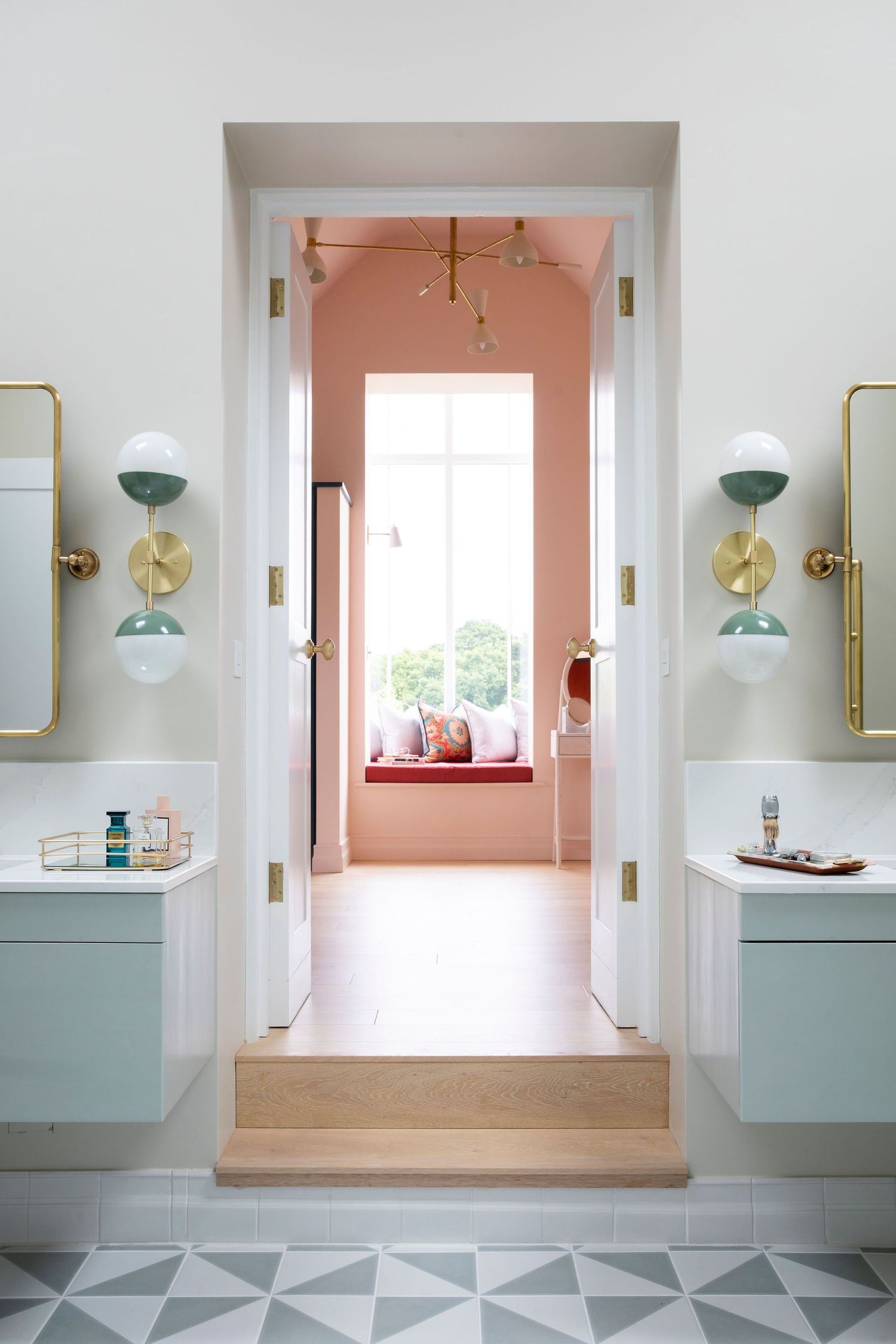 Minimalist bathroom entrance with symmetrical vanities leading to a pink-walled room with window seat.