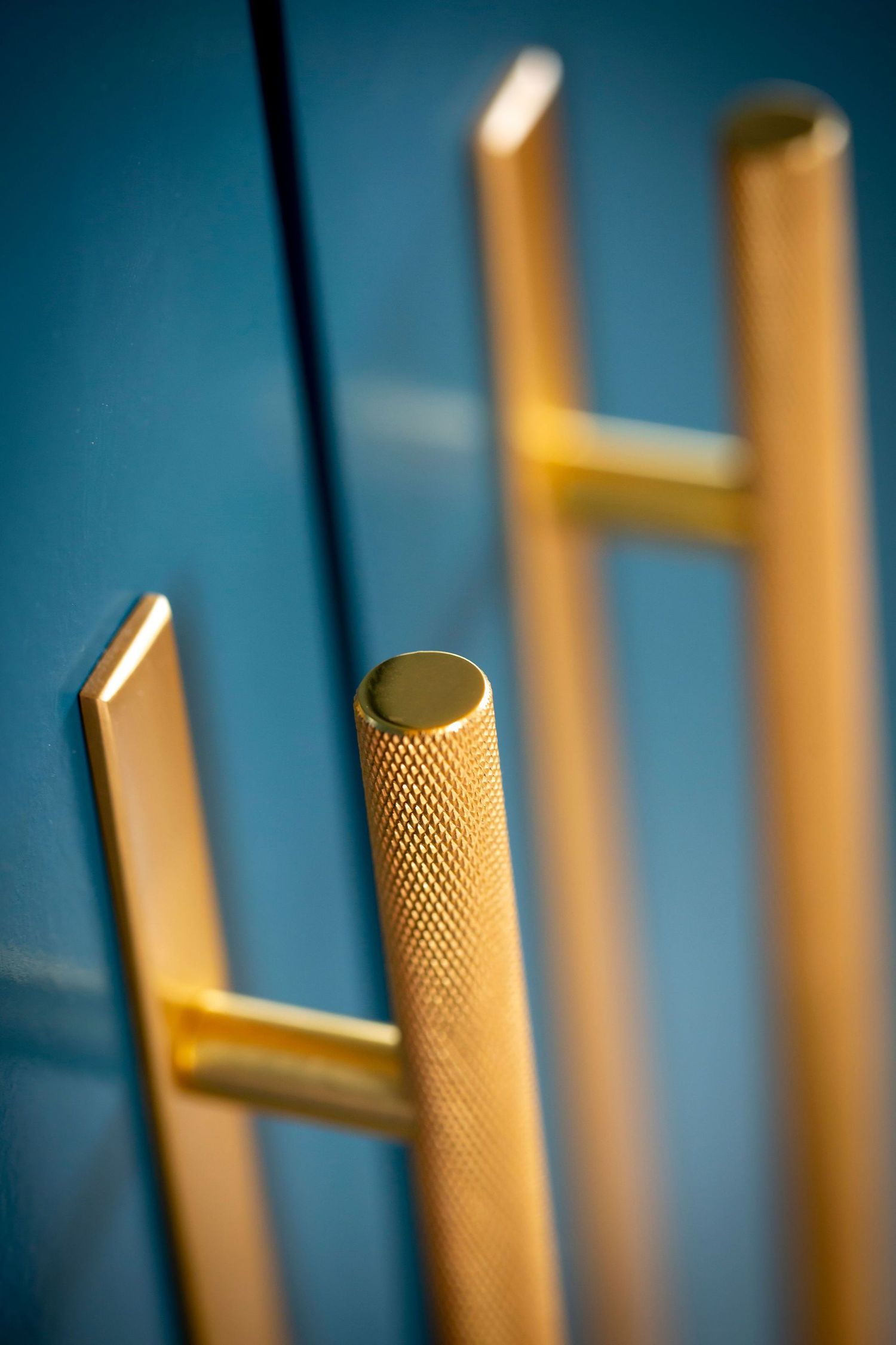 Close-up of brass knurled hooks against deep blue background.