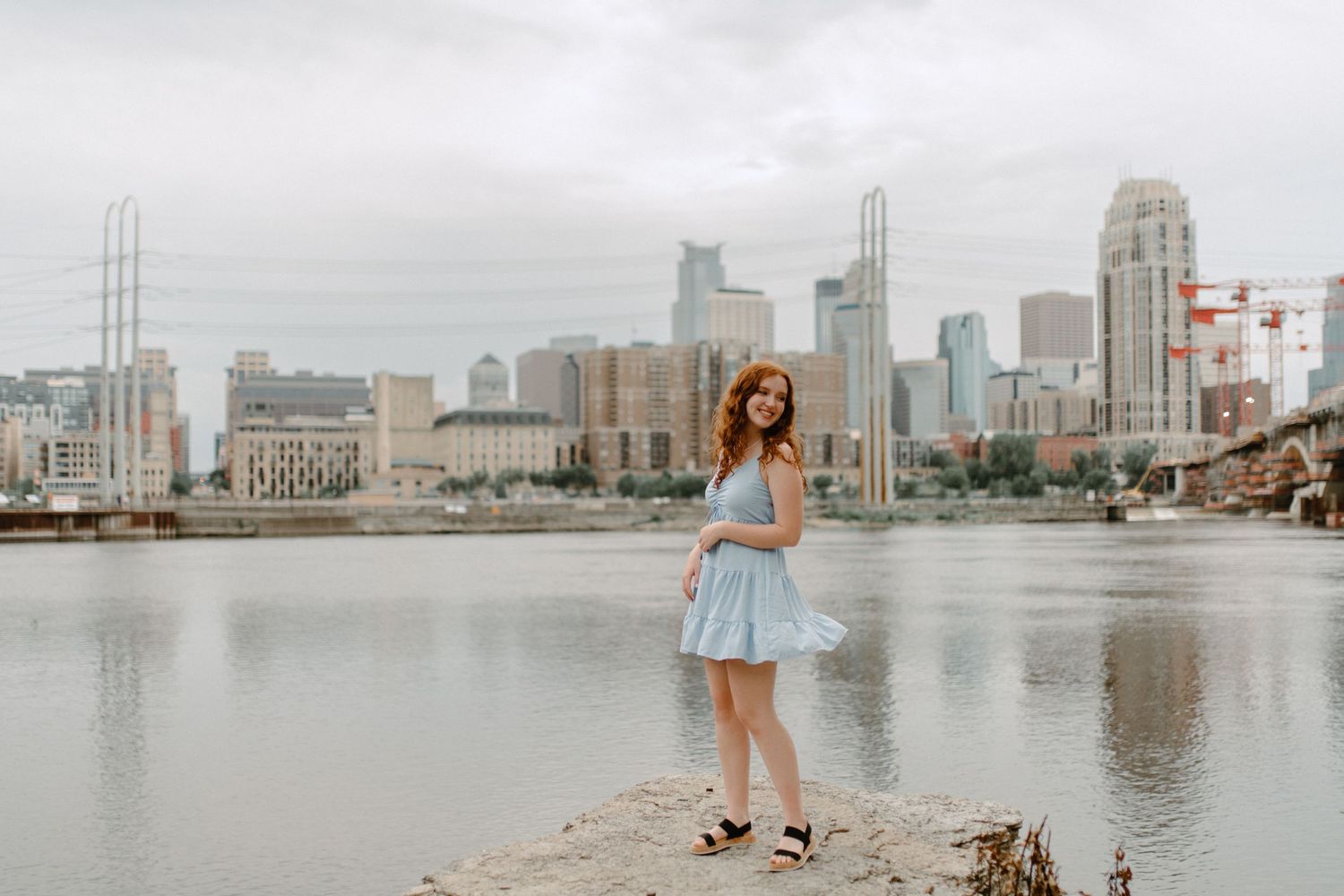 A whimsical portrait by the waterfront with a city skyline backdrop.