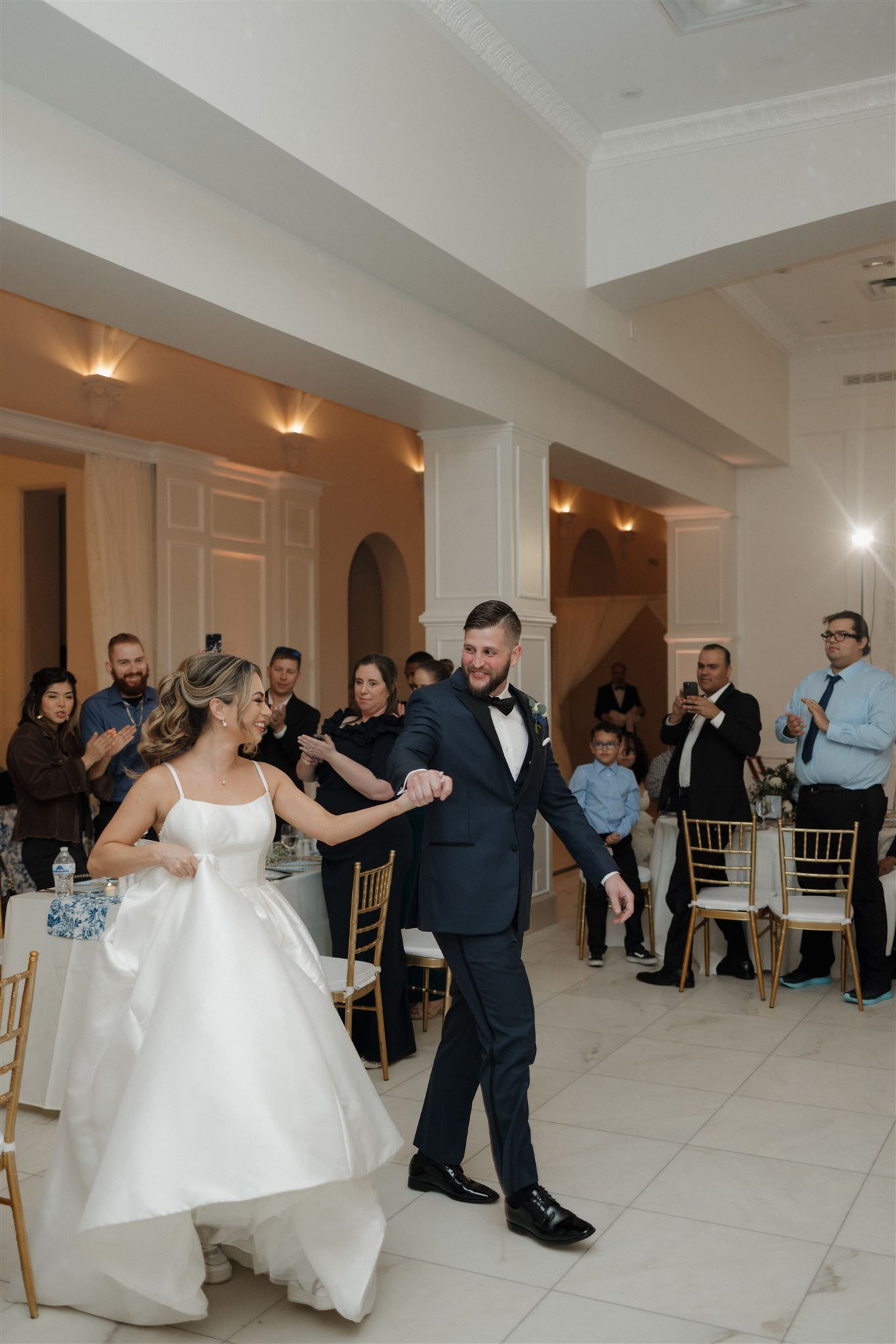 Wedding celebration with dancing in an elegant white ballroom venue.