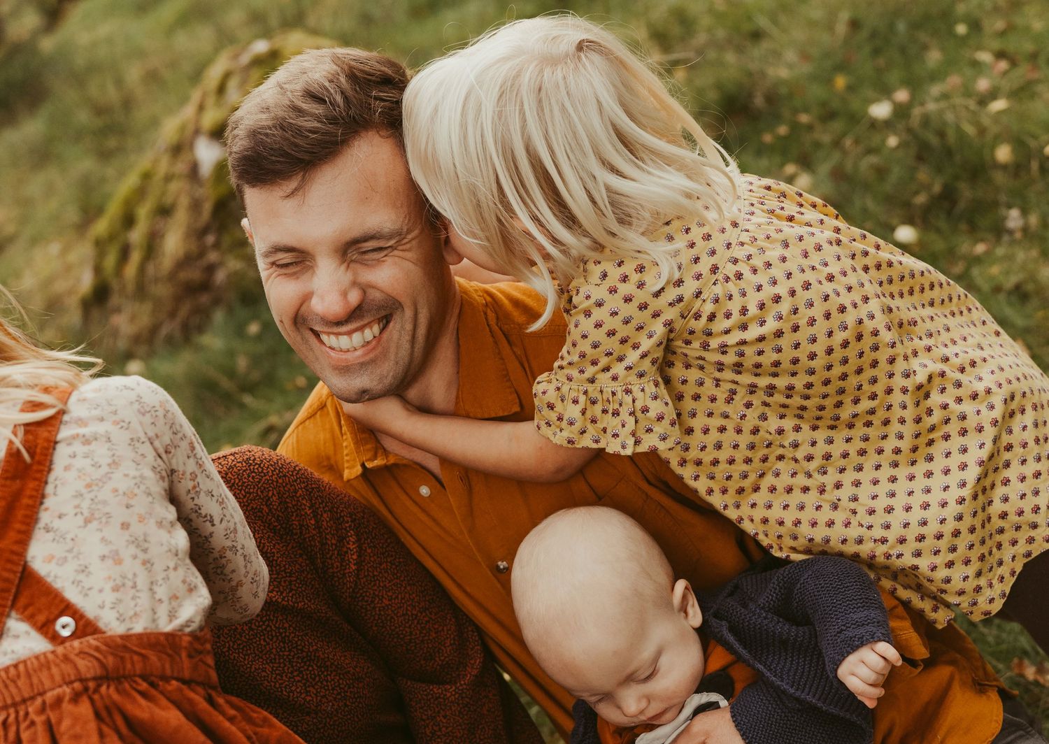 Candid family moment captured outdoors with warm autumn colors and natural lighting.