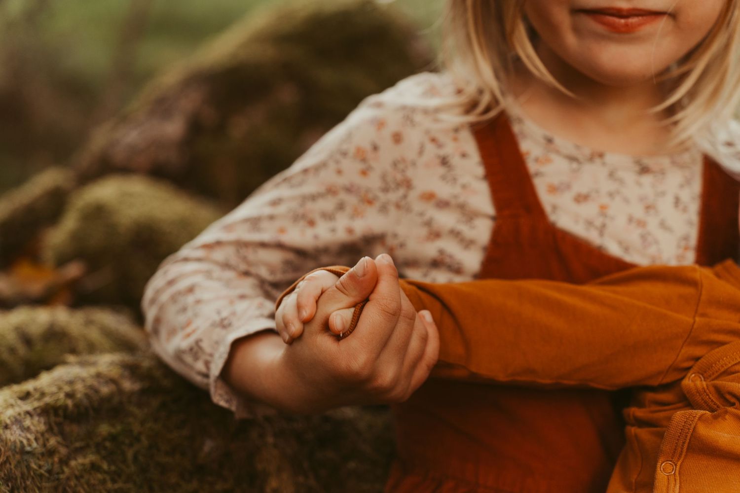 Close-up detail shot of hands in rustic autumn clothing against a natural background.