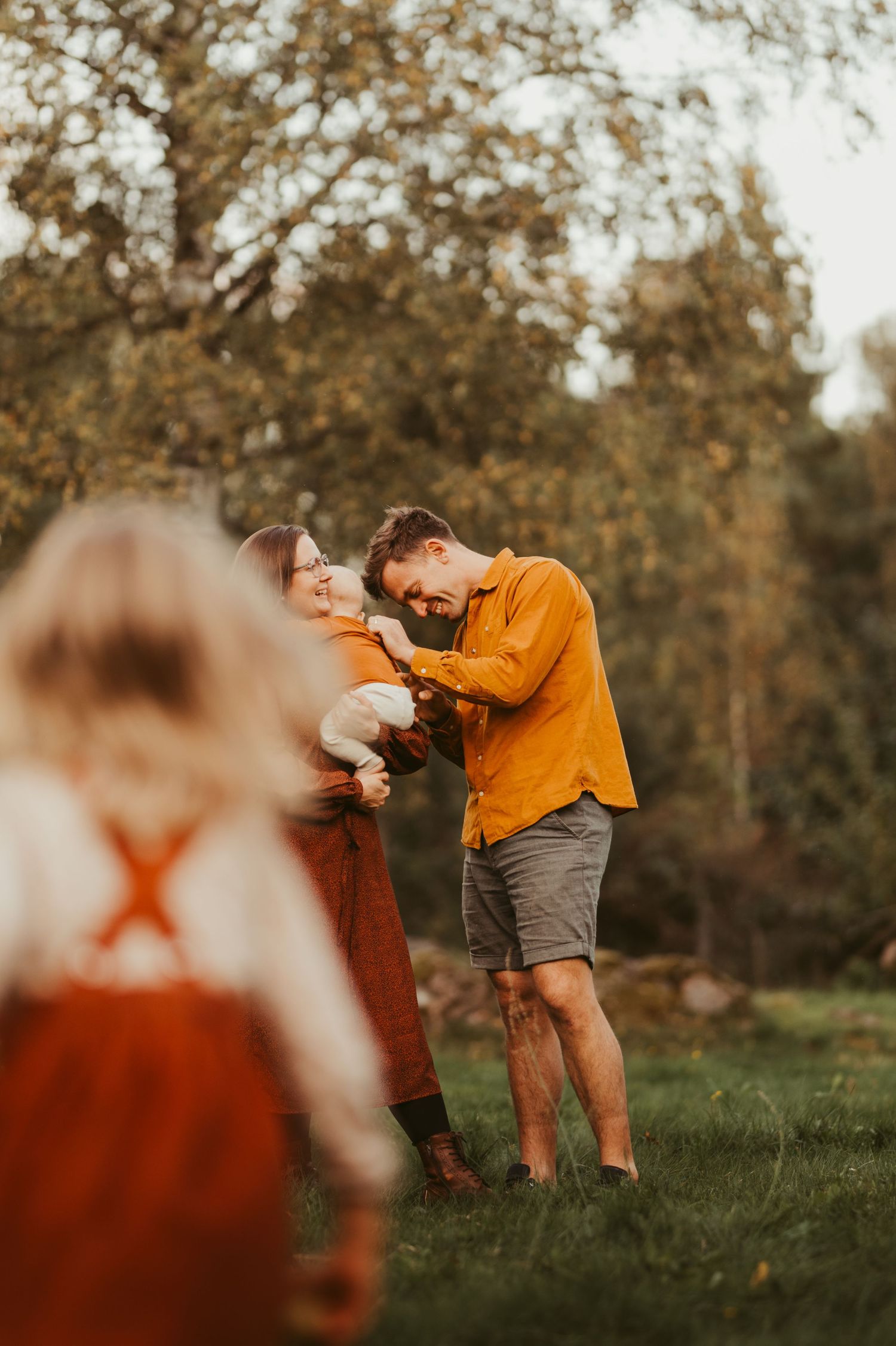 Candid family moment captured through foreground elements in warm golden light.