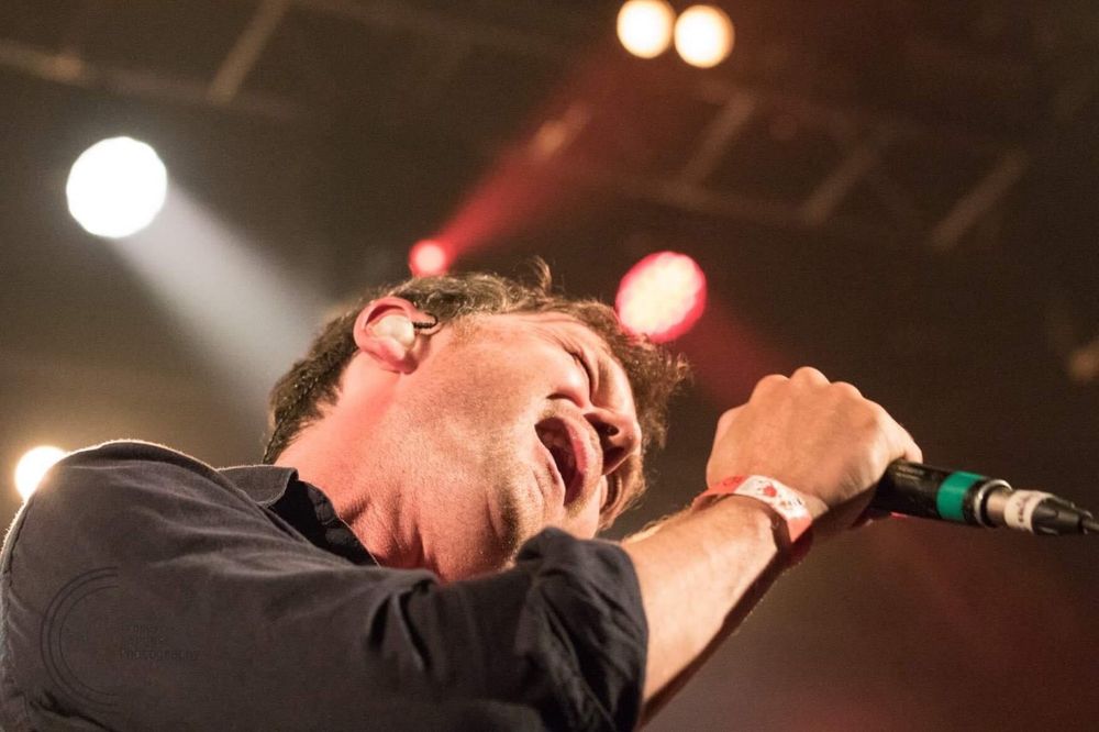Concert performer passionately singing into microphone under dramatic stage lighting. Edinburgh Leith for Hidden Door Arts Festival