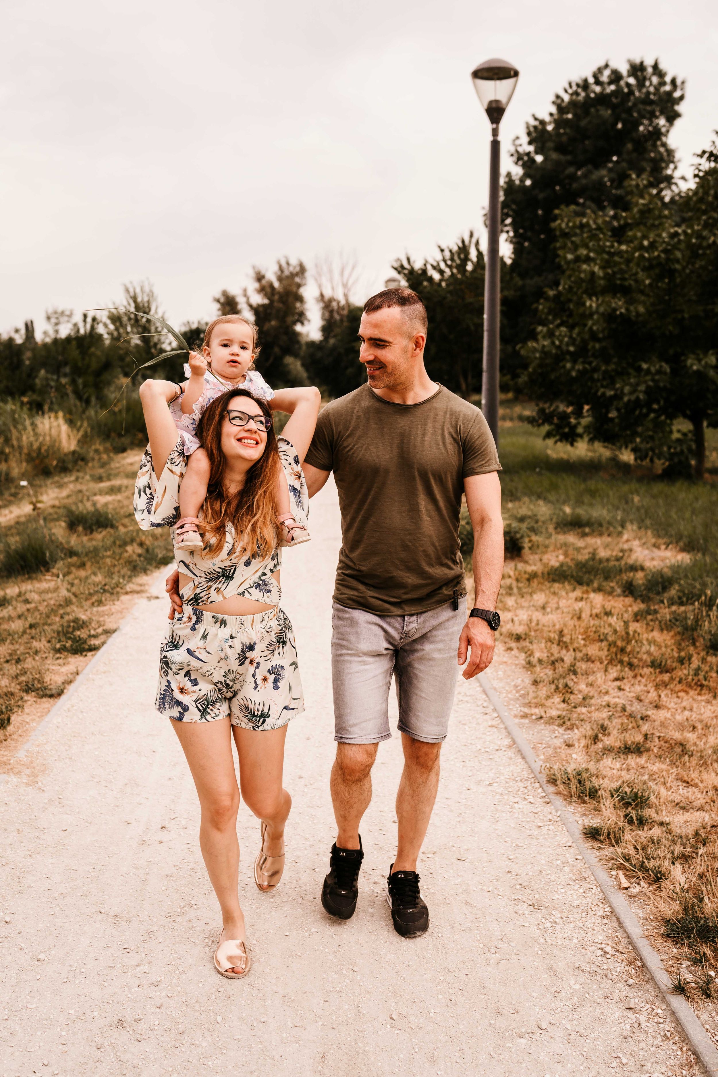 Family walking together and laughing on a paved pathway surrounded by greenery.