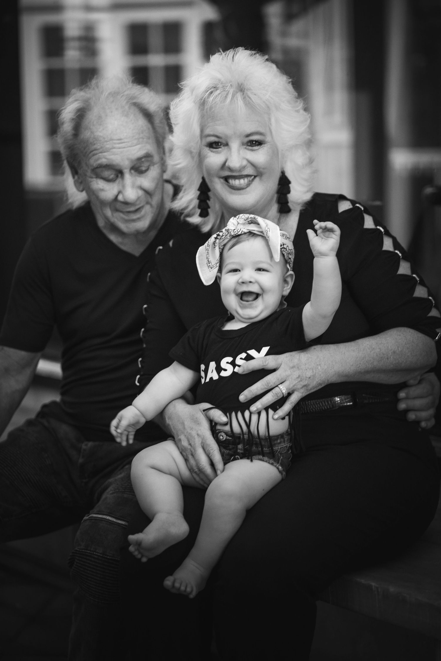 A heartwarming black and white family portrait showing three generations sharing joyful laughter together.