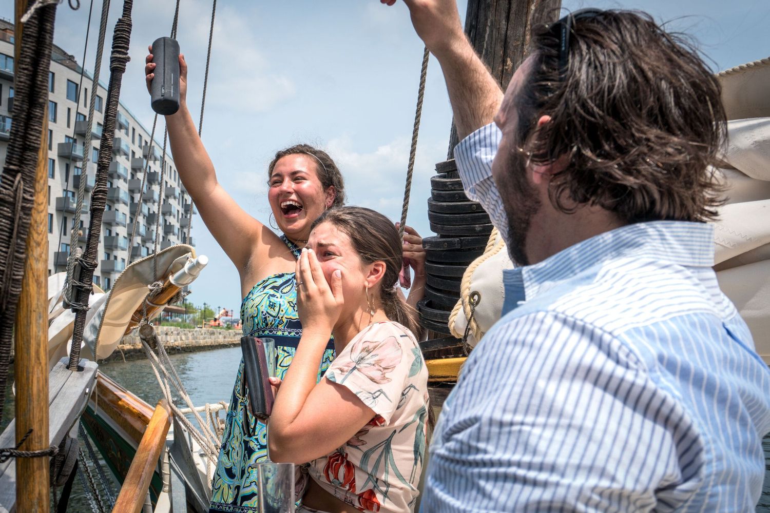 Group celebrating with drinks on deck of sailing vessel.