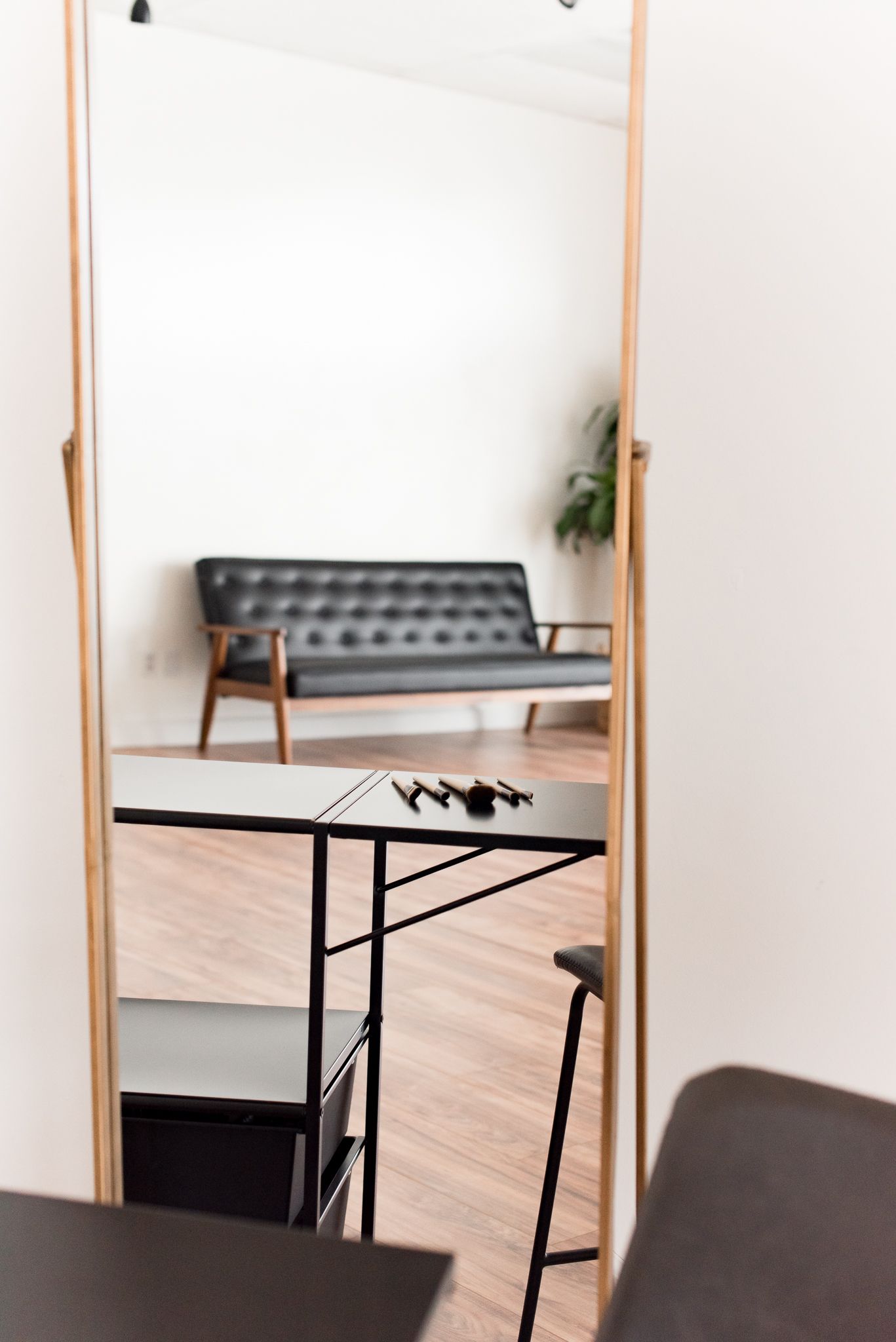 Black couch and makeup brushes reflection in floor mirror