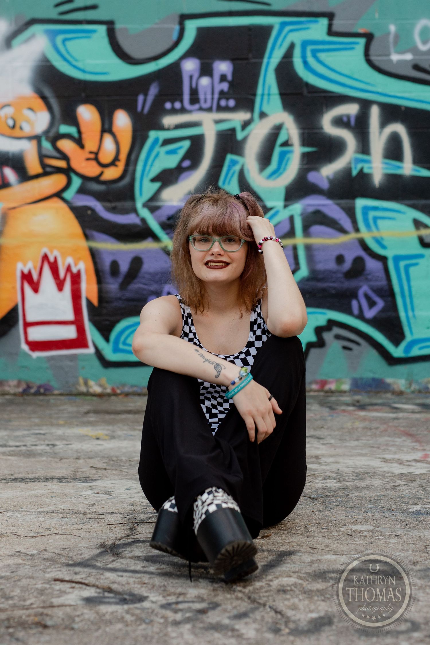 Casual portrait against vibrant blue and turquoise graffiti wall showcasing street style fashion.